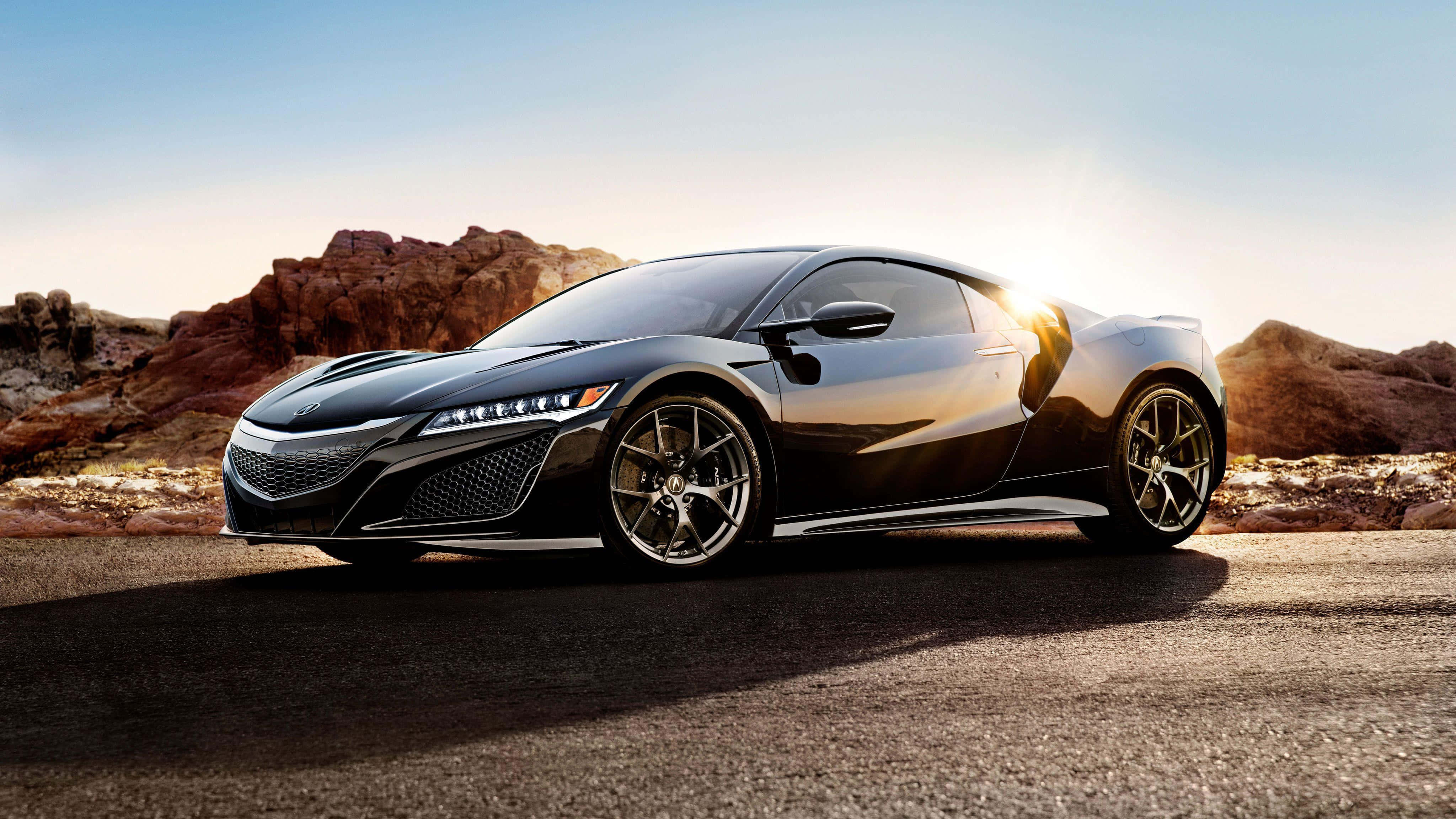 Acura Nsx 桌布 壁紙 — 一輛時尚的黑色跑車在金色夕陽下閃耀，背景是崎嶇的沙漠岩石地貌。