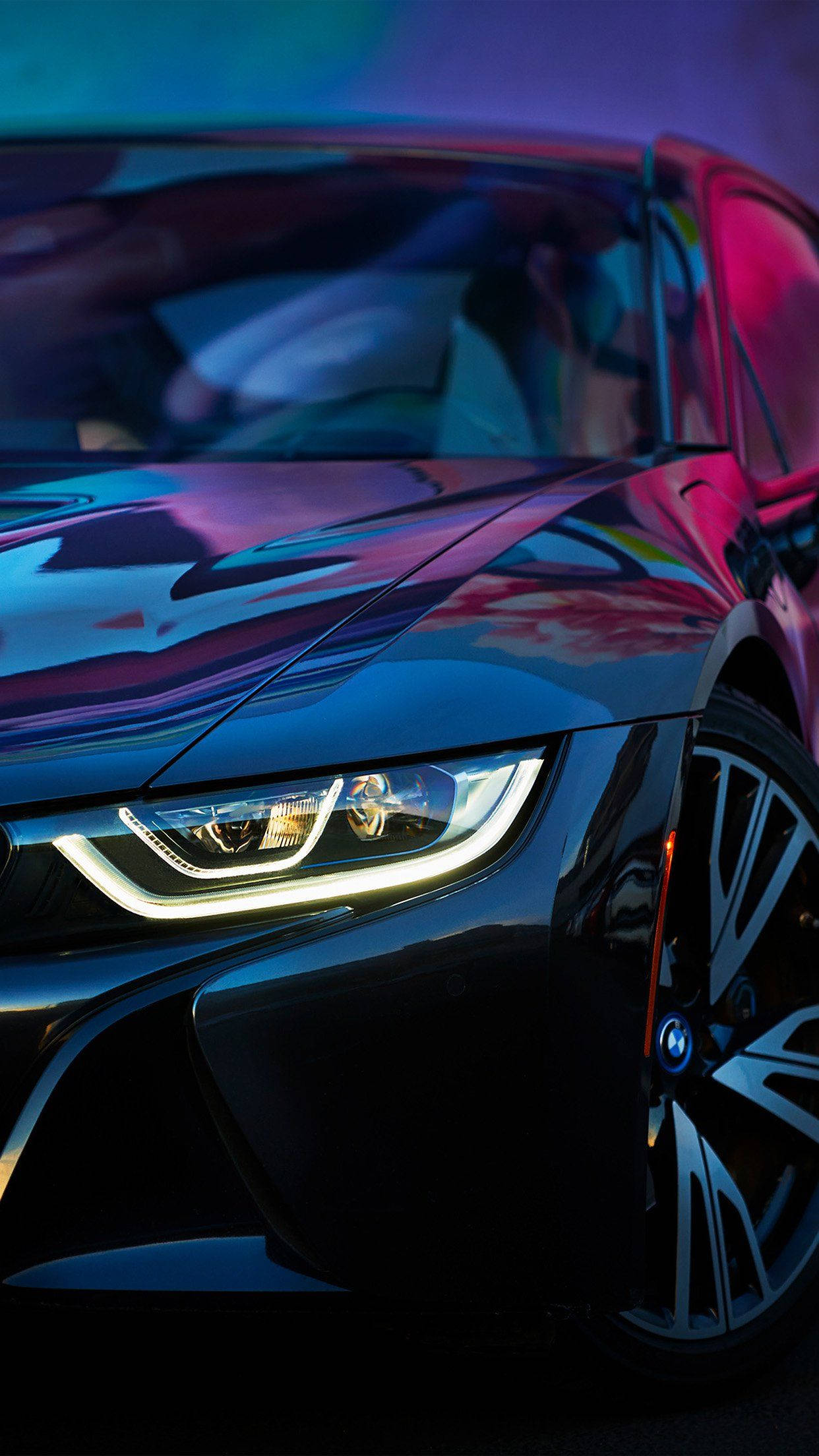 BMW 動圖 桌布 壁紙 — 一輛時尚的黑色跑車在霓虹燈下閃耀，其光滑表面上有充滿活力的紫色和藍色反射。
