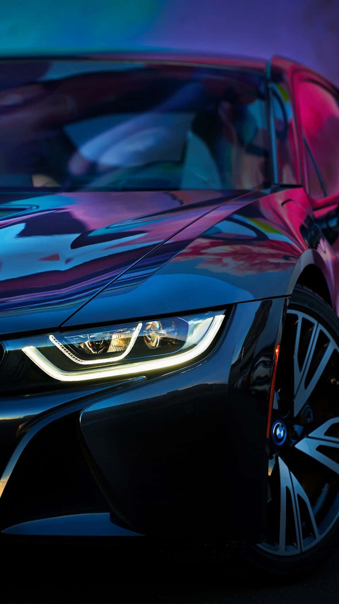 Bmw Android 桌布 壁紙 — 一輛時尚的黑色跑車在鮮豔的霓虹燈下閃閃發光，燈光反射在其光滑的表面。
