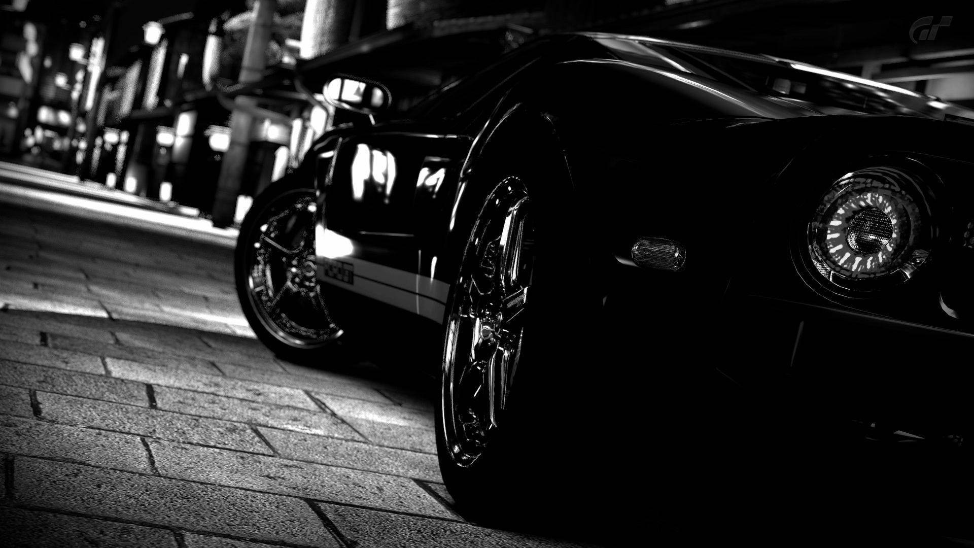 跑車 桌布 壁紙 — 一輛時尚的黑色跑車在鵝卵石街道上，在戲劇性的夜間燈光下閃閃發光。