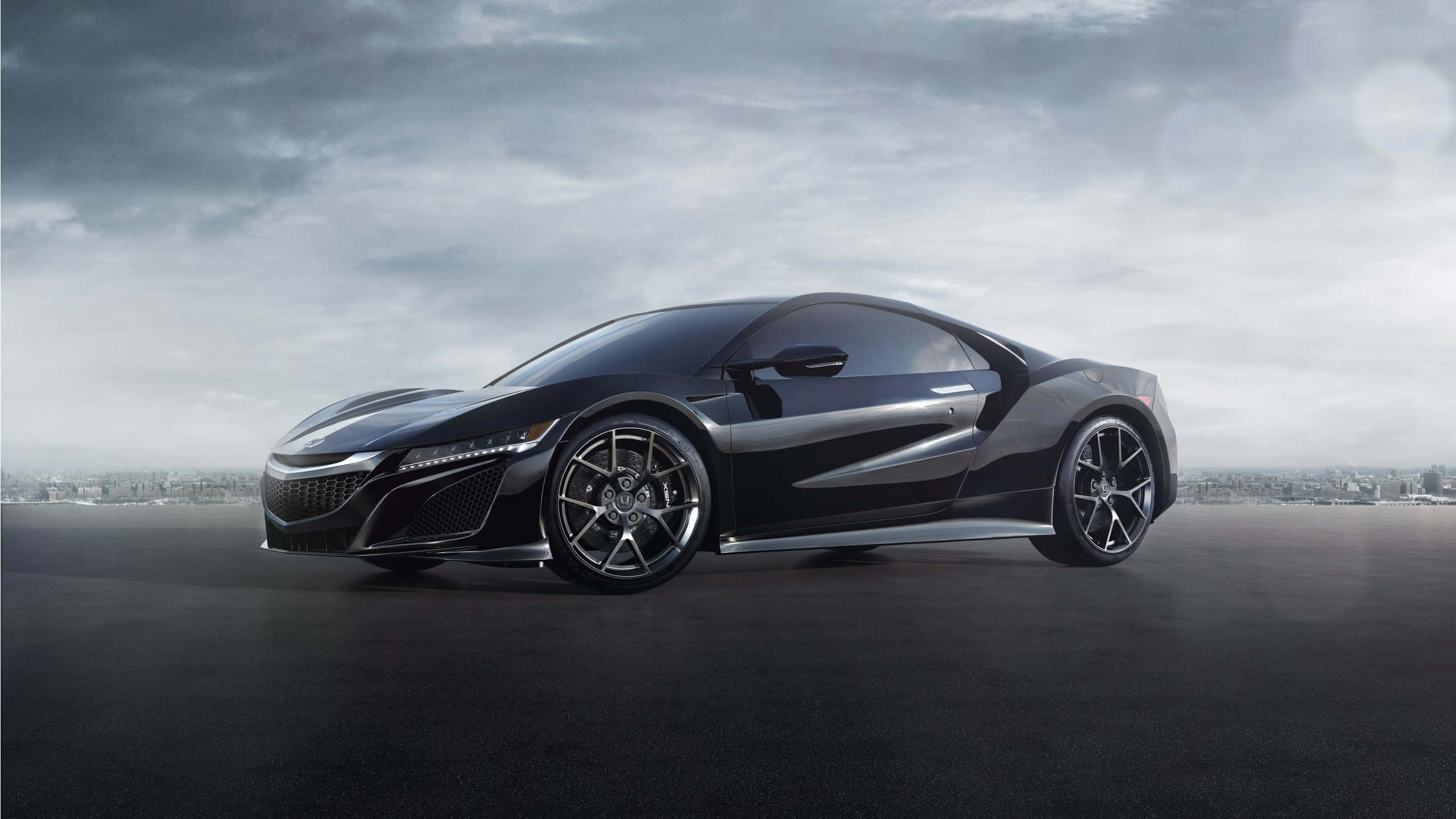 Honda Nsx 桌布 壁紙 — 一輛時尚的黑色跑車帶有銀色裝飾，在陰天下的深色瀝青路面上閃閃發光。