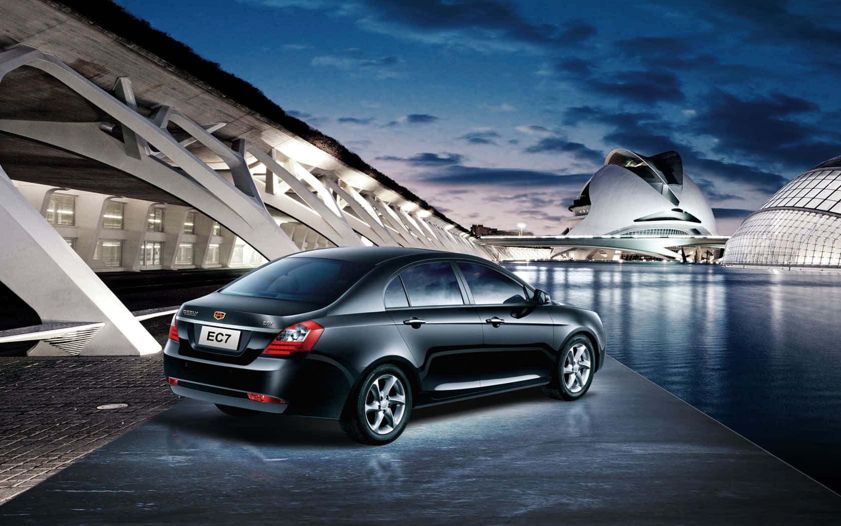 Geely 桌布 壁紙 — 一輛時尚的黑色轎車停放在反光的濕滑路面上，背景是暮色天空下閃爍著未來主義建築的光芒。