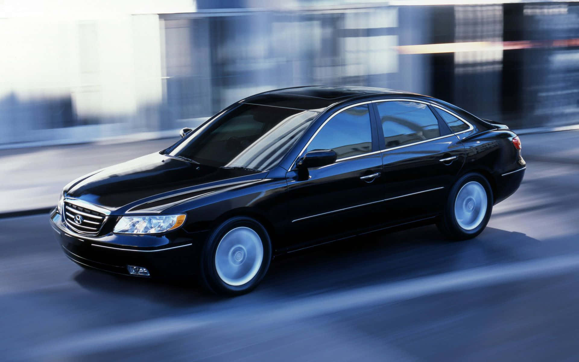 Hyundai Azera 桌布 壁紙 — 一輛時尚的黑色轎車在模糊的城市街道上疾馳，動態模糊強調了速度。