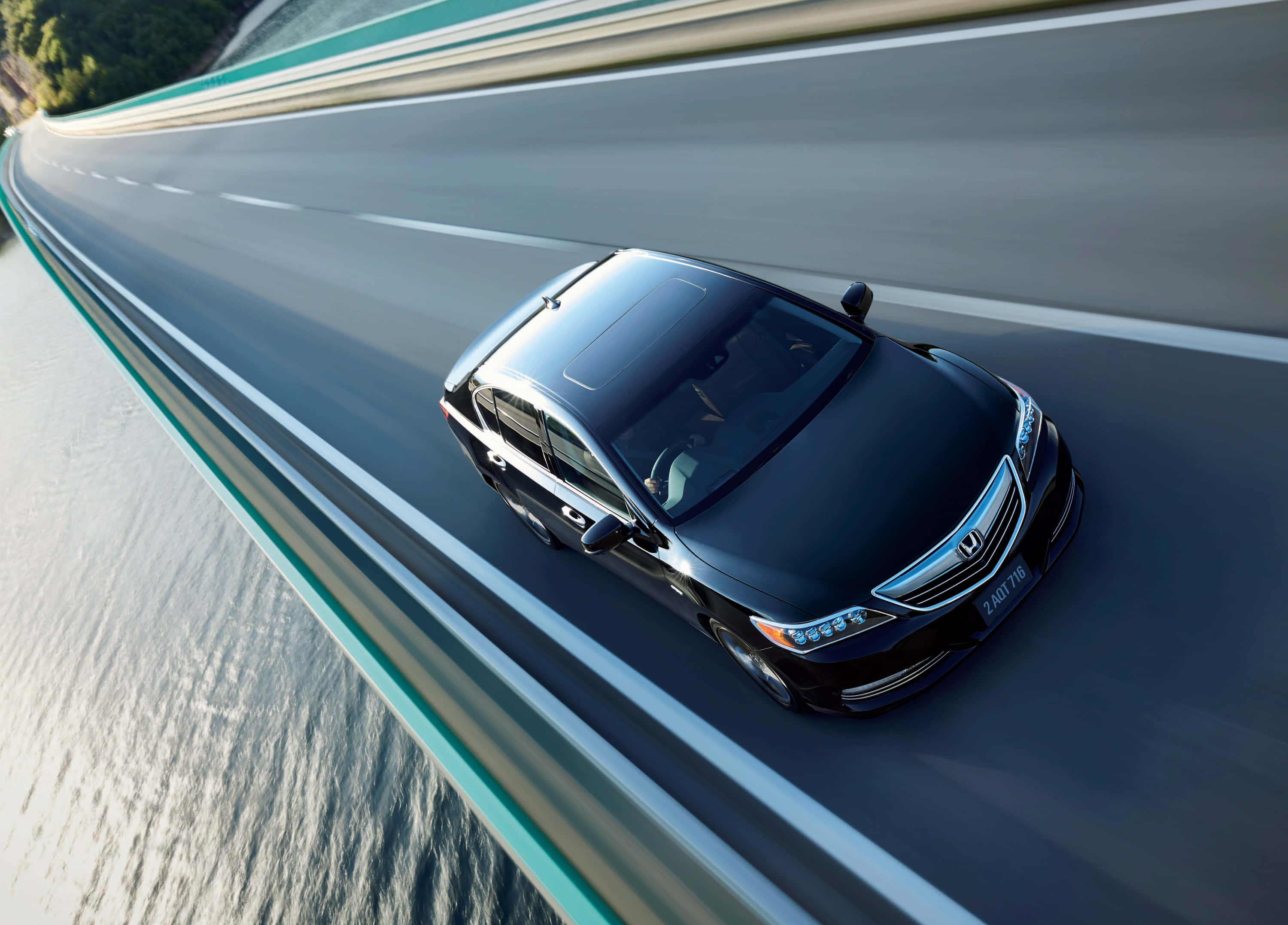 Honda Legend 桌布 壁紙 — 一輛時尚的黑色轎車沿著蜿蜒的海岸高速公路行駛，配有藍綠色護欄和下方閃爍的大海。