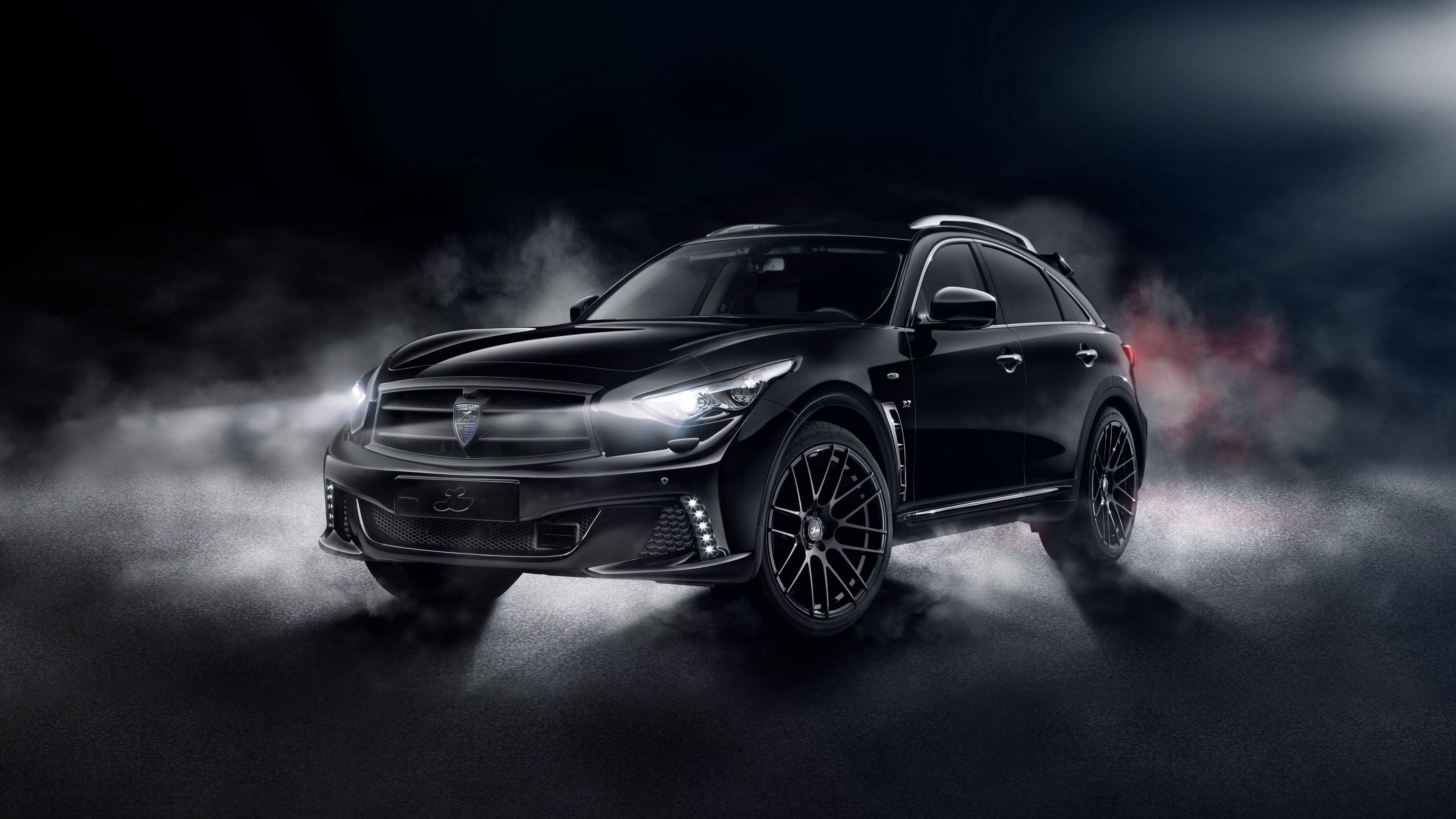 Infiniti 桌布 壁紙 — 一輛時尚的黑色運動型SUV從黑暗的迷霧中出現，帶有發光的頭燈和紅色排氣火焰，在戲劇性的燈光下。