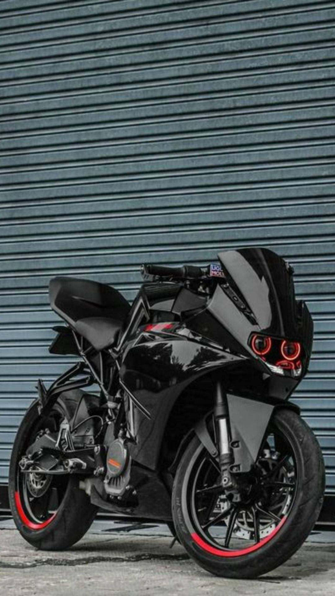KTM RC 200 桌布 壁紙 — 一輛時尚的黑色運動機車帶有紅色點綴，停靠在波紋金屬車庫門前。