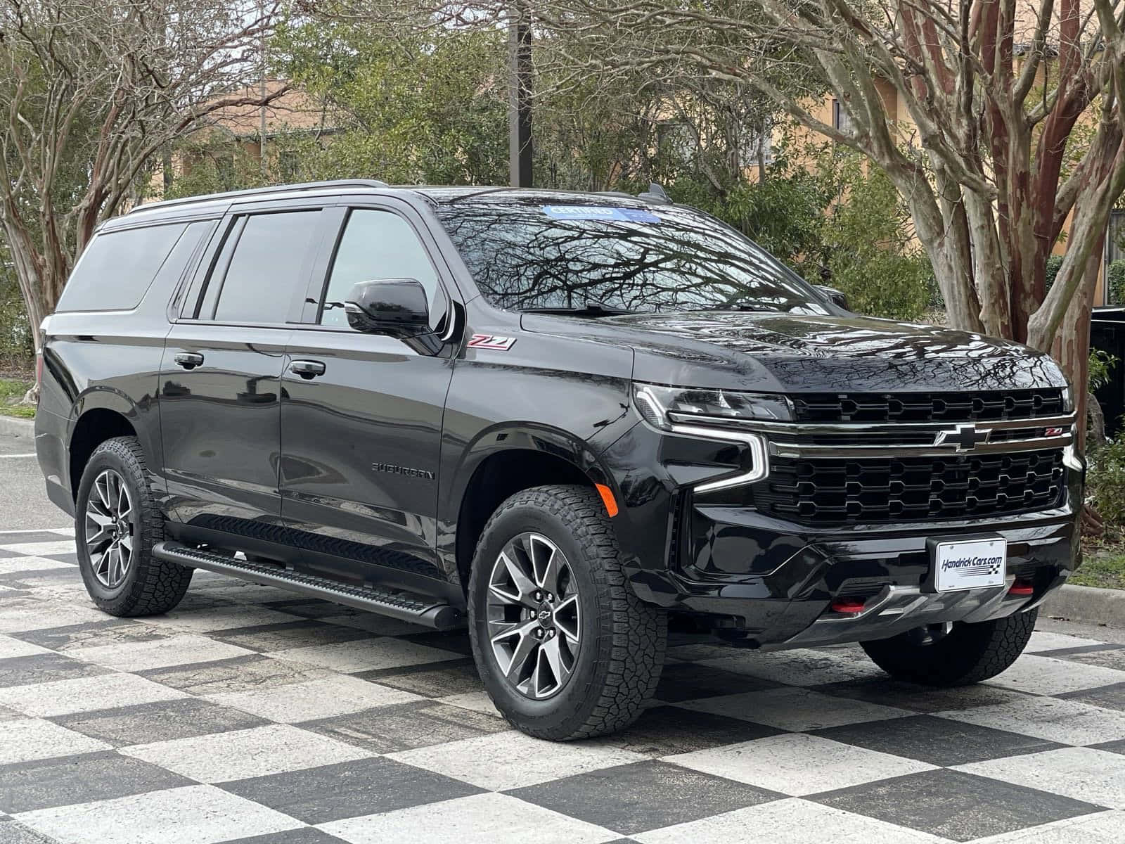 Chevrolet 桌布 壁紙 — 一輛時尚的黑色雪佛蘭 Suburban Z71 SUV 停放在棋盤格路面，周圍是落葉樹木。