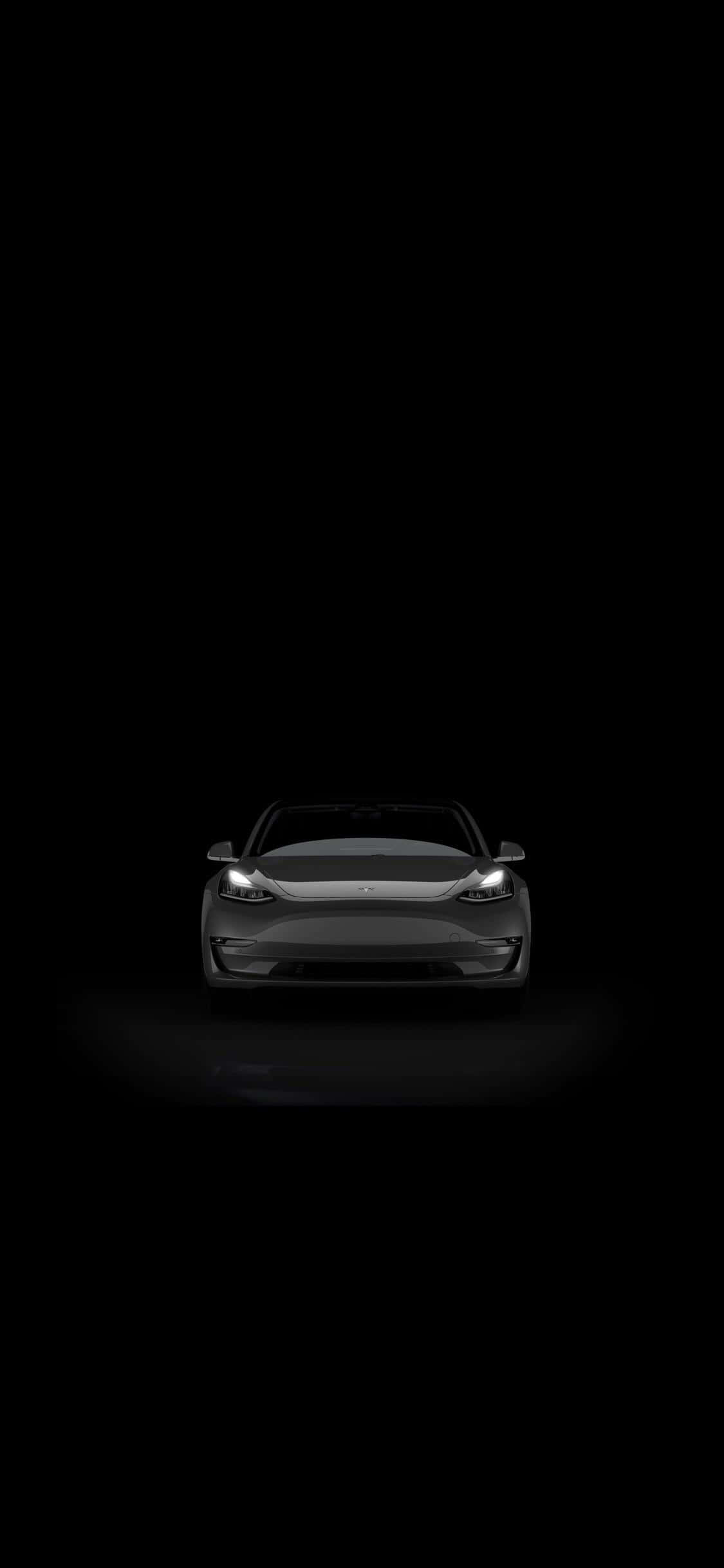 特斯拉 桌布 壁紙 — 一輛時尚的黑色電動車在漆黑虛空中閃爍著明亮的車頭燈。