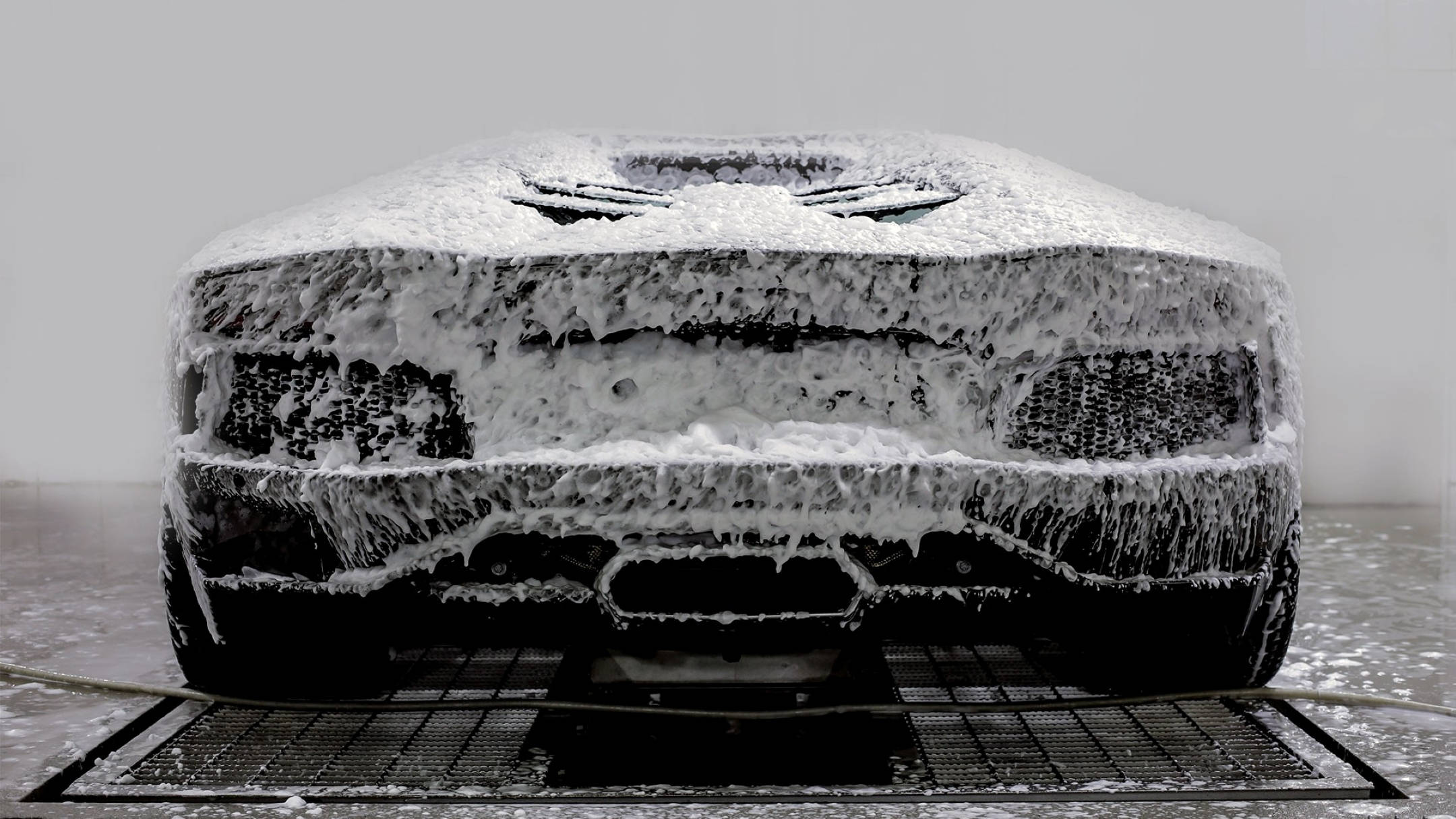 Wash 桌布 壁紙 — 一輛時尚跑車在自動洗車過程中完全被厚厚的白色泡沫覆蓋，水從其表面滴落。