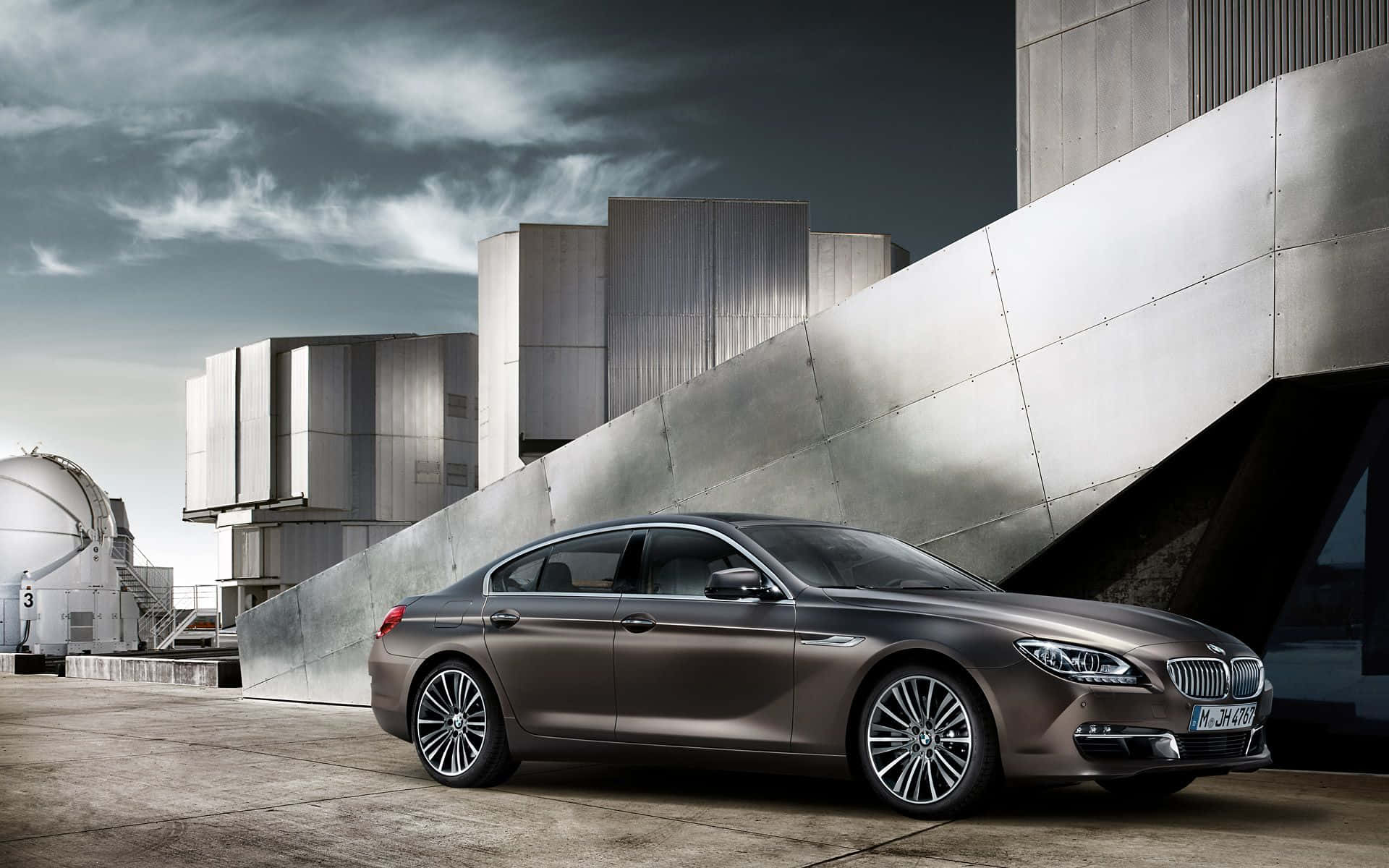 Bmw 6 Series 桌布 壁紙 — 一輛時尚金屬棕色BMW 6系列轎車停放在現代棱角建築旁，天空多雲。