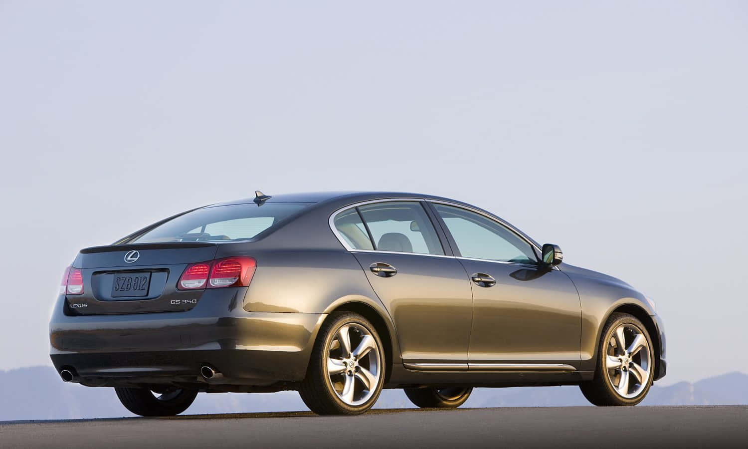 Lexus Gs 桌布 壁紙 — 一輛時尚金屬灰色Lexus GS 350轎車停泊在道路上，遠山在淡色天空下。