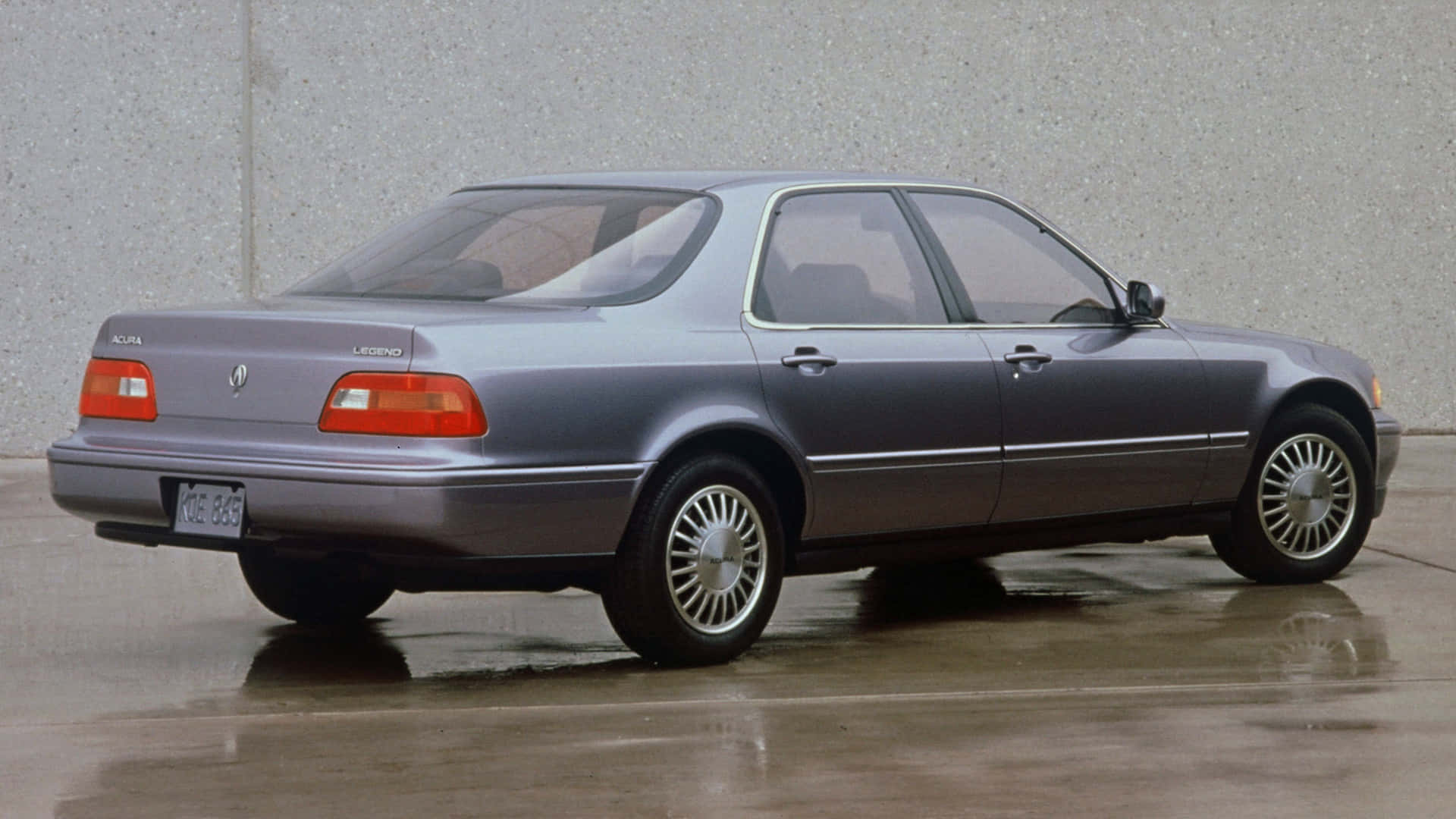 Acura Legend 桌布 壁紙 — 一輛時尚銀色Acura Legend轎車停放在濕滑路面上，背景是灰色混凝土牆。