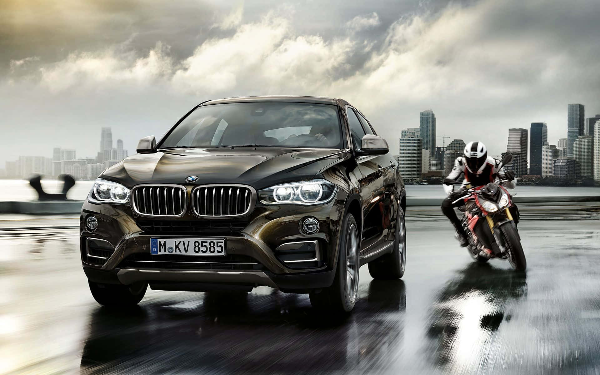 Bmw Cars 桌布 壁紙 — 一輛時尚黑色BMW X6 SUV與一輛紅色摩托車在暴風雨天空下，於濕滑的城市橋上並肩奔馳。