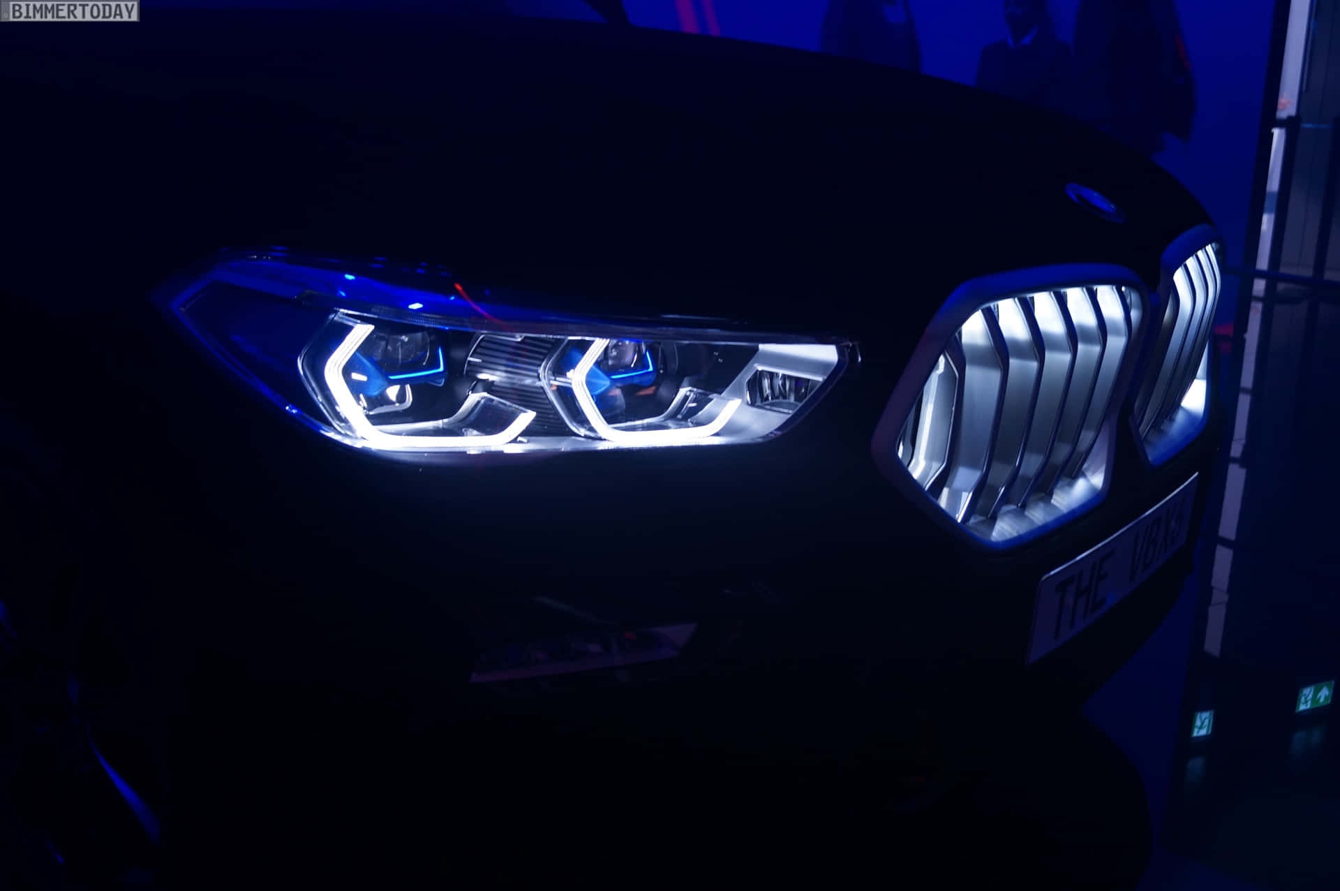 Vantablack 桌布 壁紙 — 一輛時尚黑色BMW汽車的發光頭燈和標誌性格柵在黑暗的室內環境中，在戲劇性的藍色燈光下閃耀。