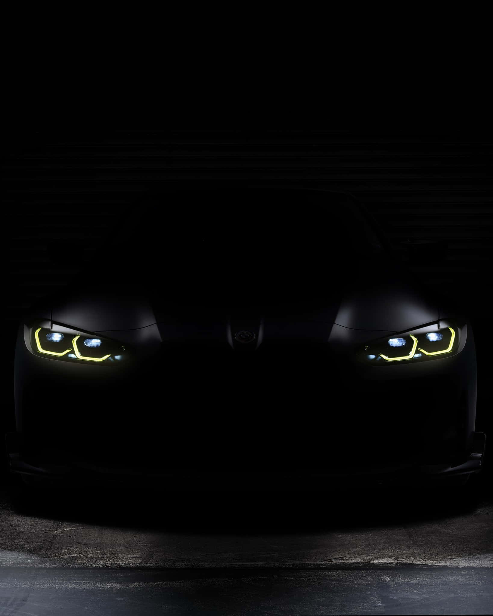 Imminent 桌布 壁紙 — 一輛時尚黑色BMW汽車的發光黃色和藍色車頭燈在戲劇性的低角度鏡頭中刺穿黑暗。