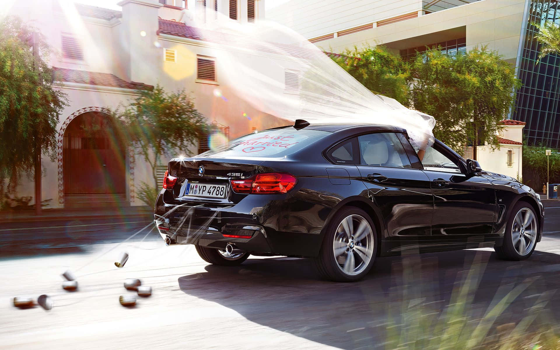 Bmw 4 Series 桌布 壁紙 — 一輛時尚黑色BMW轎車在陽光明媚的城市街道上疾馳，散落香檳瓶並噴出氣泡。