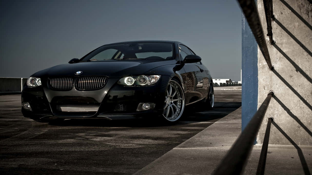 720p Bmw 桌布 壁紙 — 一輛時尚黑色BMW雙門轎跑車停在工業屋頂，附近有戲劇性的陰影和混凝土牆。