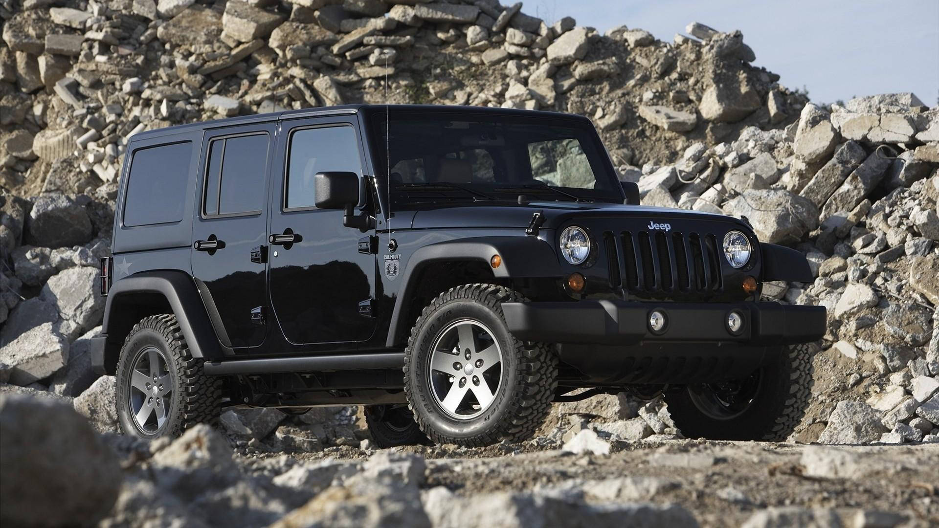 Wrangler 桌布 壁紙 — 一輛時尚黑色Jeep Wrangler在晴朗日光下矗立在崎嶇岩石地形上。