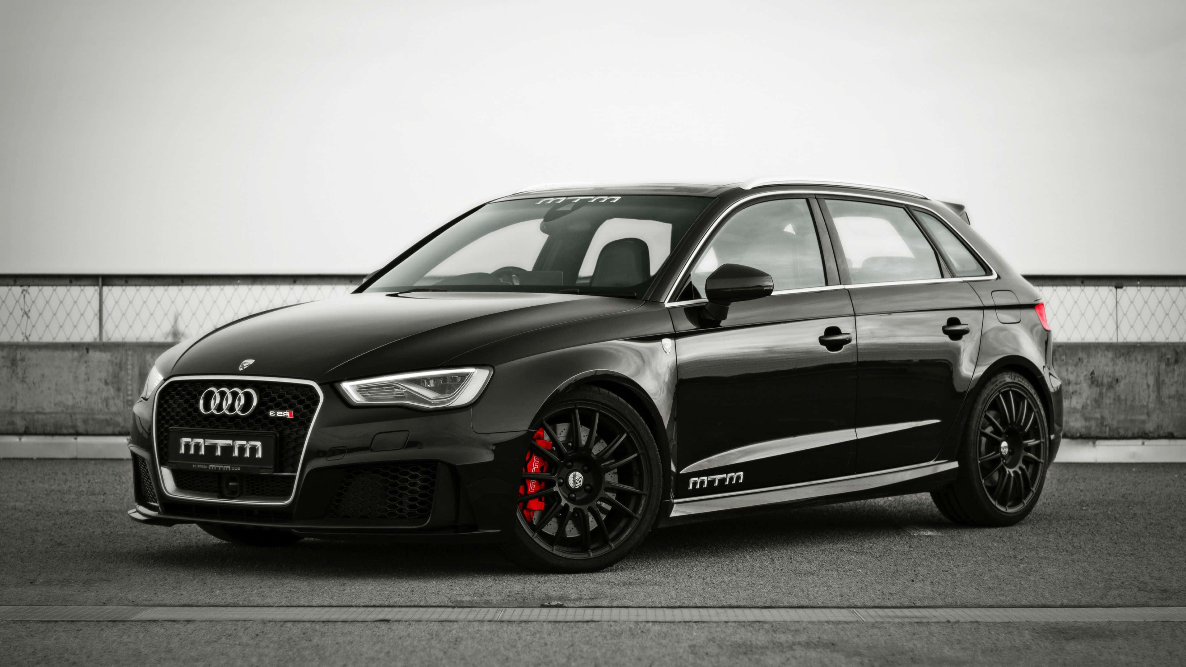 Audi Rs3 桌布 壁紙 — 一輛時尚黑色MTM改裝奧迪RS3 Sportback，配備紅色制動卡鉗，停放在瀝青賽道上。