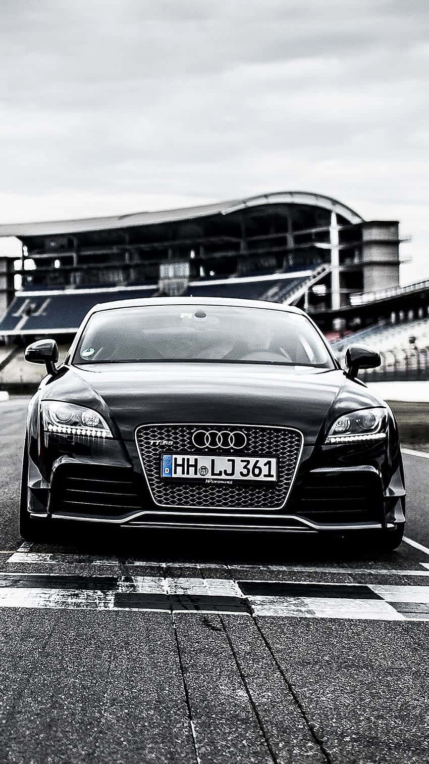 Audi Tt Rs 桌布 壁紙 — 一輛時尚黑色奧迪TT RS在陰天下停放在賽車場的起跑線。