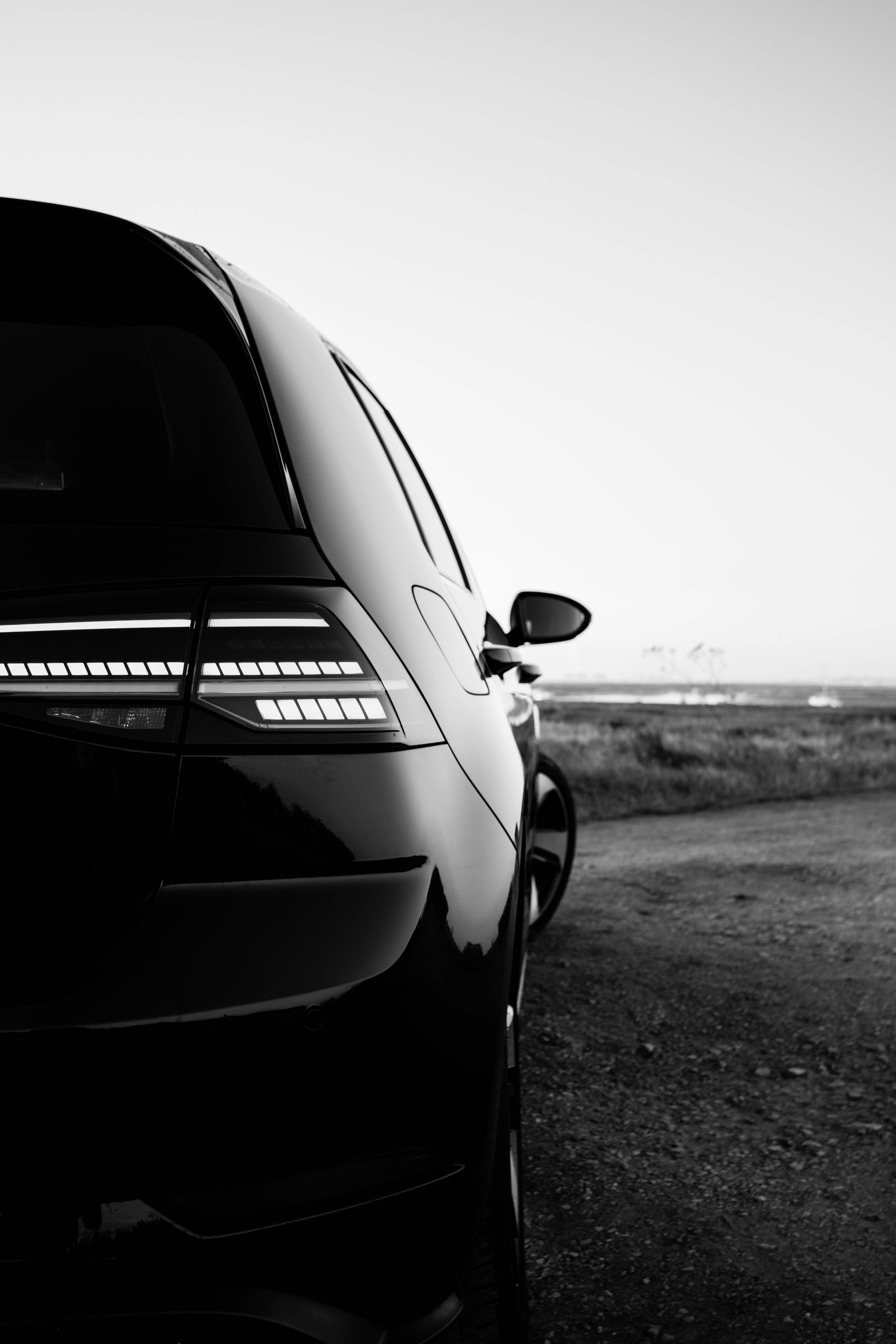 Gti 桌布 壁紙 — 一輛時尚黑色汽車的尾燈在黃昏時的極簡黑白路邊場景中閃耀。
