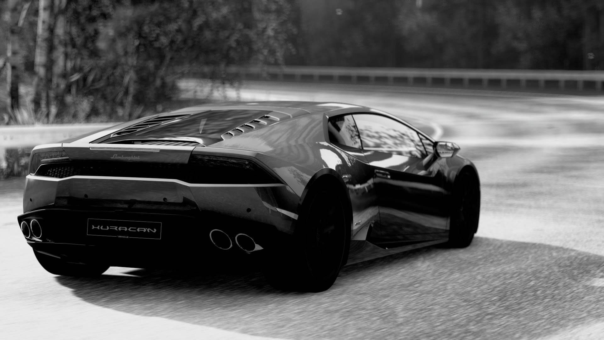 Lamborghini 4K 桌布 壁紙 — 一輛時尚黑色藍寶堅尼Huracan在單色調的模糊森林中沿著蜿蜒道路疾馳。