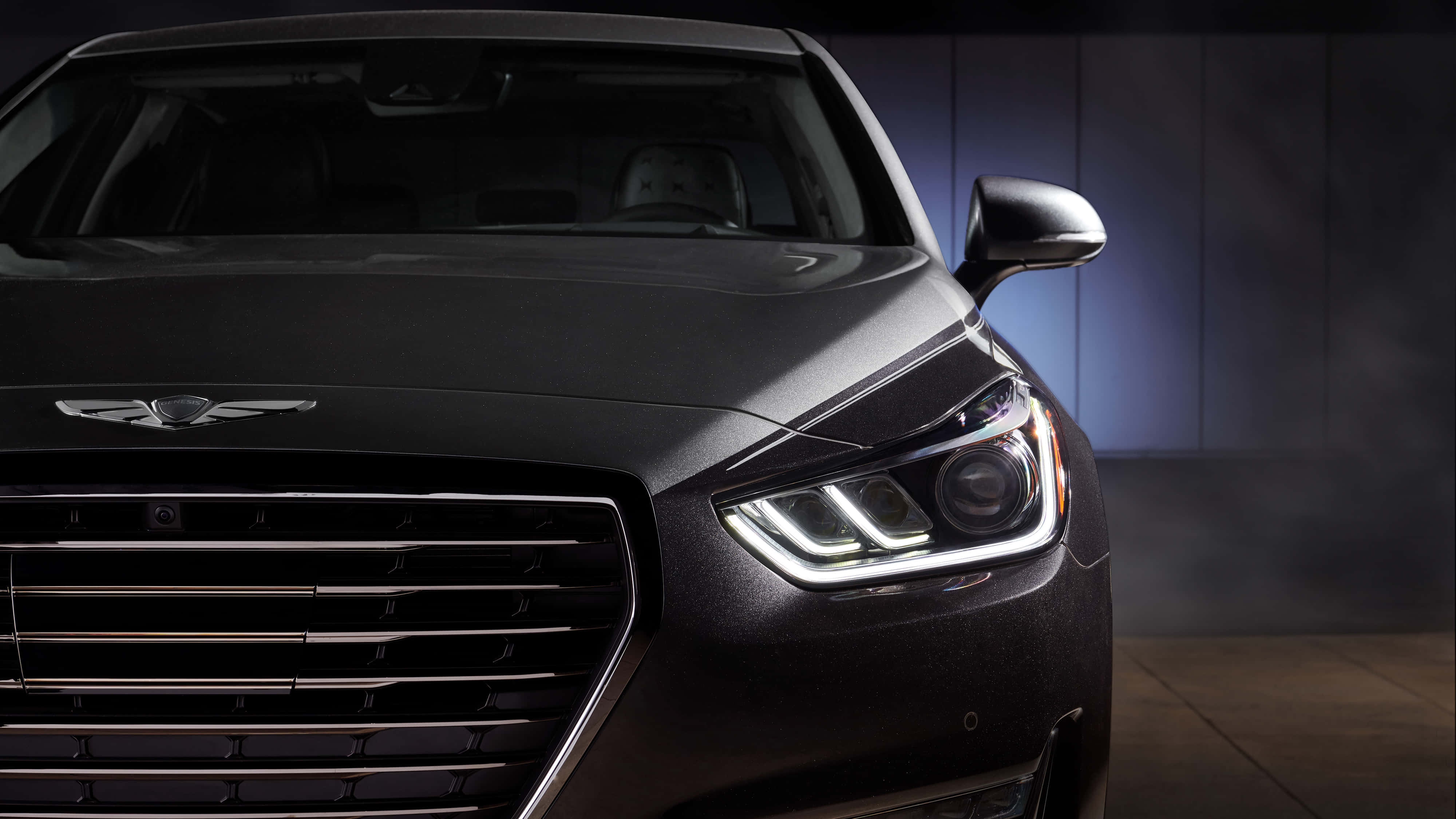 Genesis G90 桌布 壁紙 — 一輛時尚黑色豪華轎車的前臉在戲劇性的攝影棚燈光下閃耀，配備銳利的LED頭燈和鍍鉻格柵。