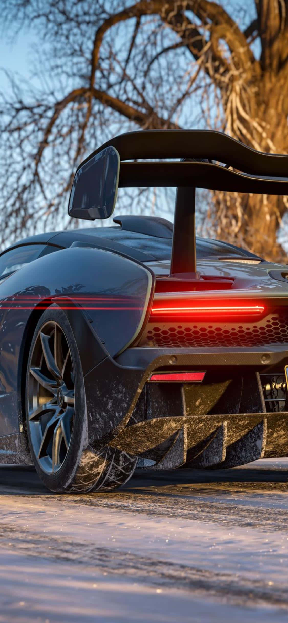 iPhone Xs Forza Horizon 4 桌布 壁紙 — 一輛時尚黑色跑車，帶有發光的紅色尾燈，停在雪地上，周圍是光禿禿的冬季樹木。