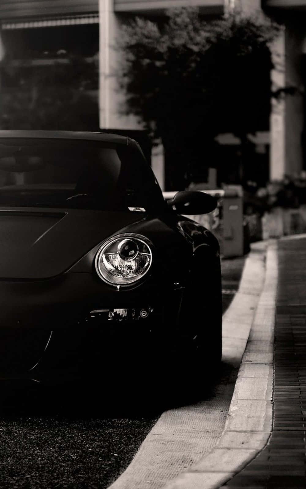 Black And White Car 桌布 壁紙 — 一輛時尚黑色跑車停放在城市高架橋下的人行道上，帶有戲劇性的單色燈光。