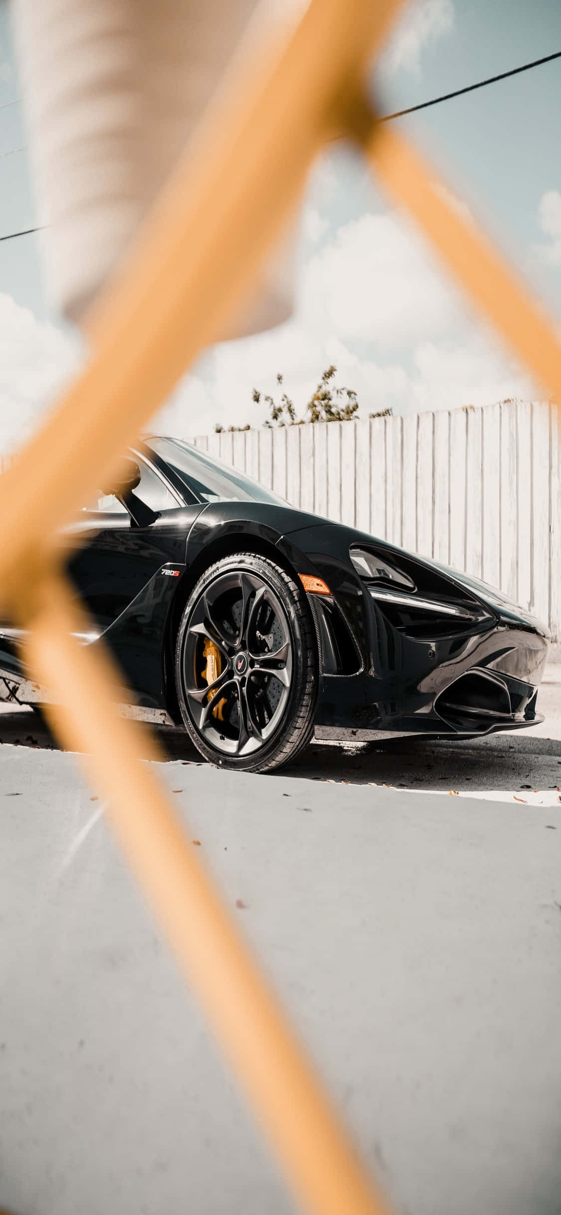 Black Car 桌布 壁紙 — 一輛時尚黑色跑車停放在木條後面，天空晴朗。