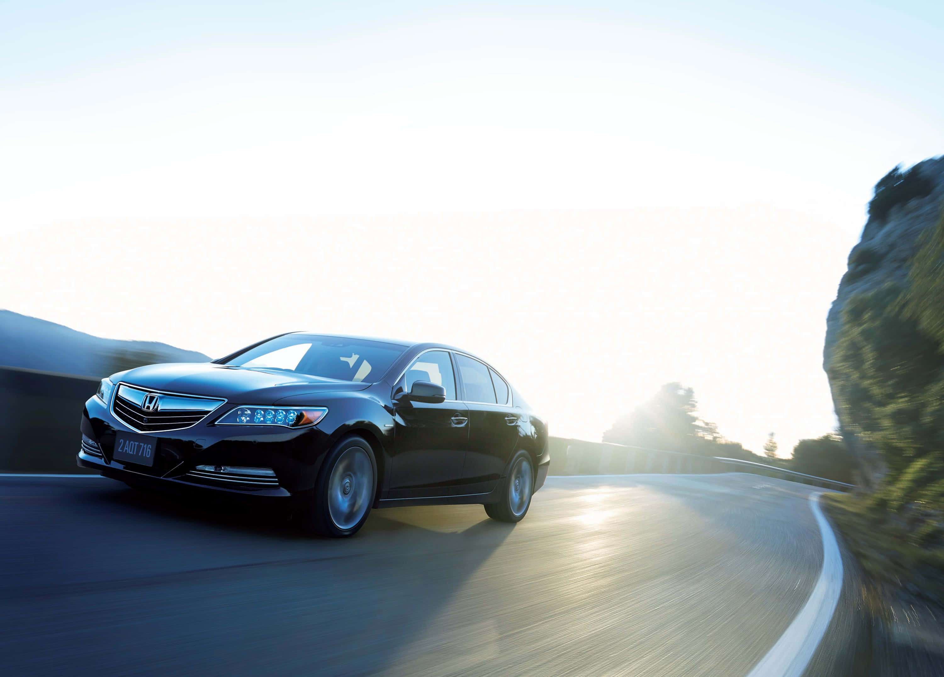 Honda Legend 桌布 壁紙 — 一輛時尚黑色轎車在沐浴著金色日出光線的蜿蜒山路上疾馳。