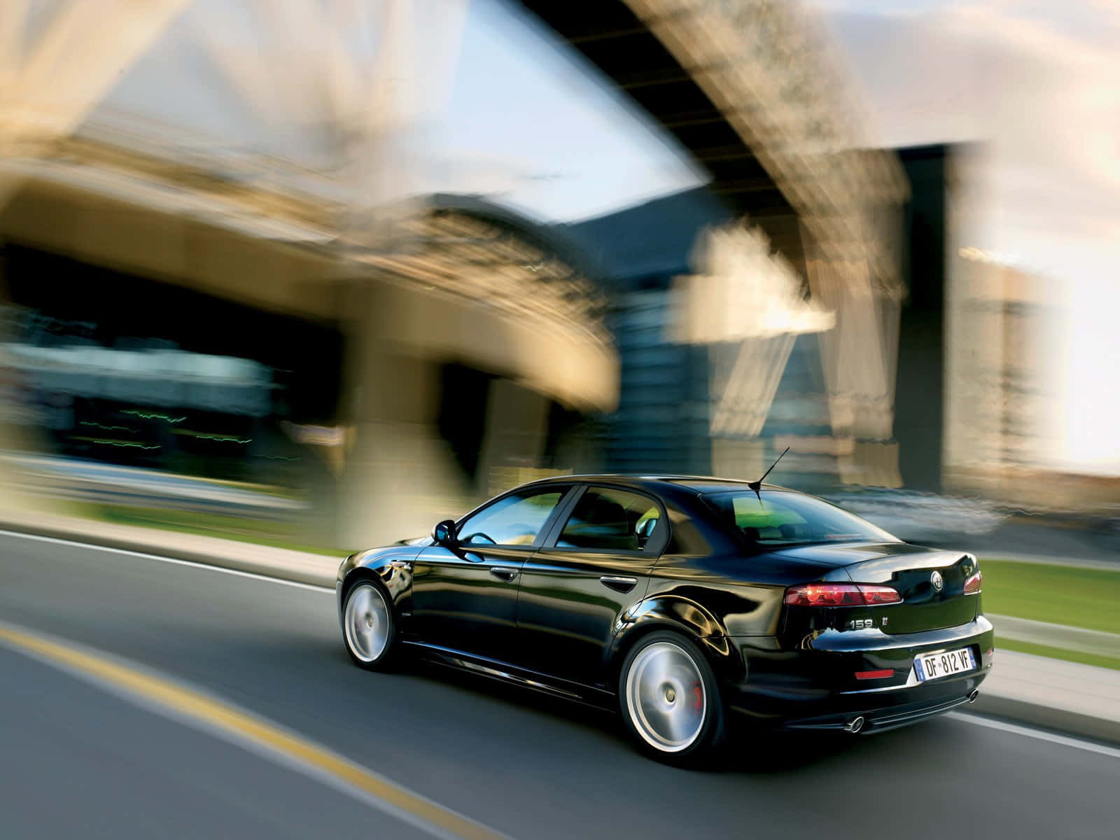 Alfa Romeo 159 桌布 壁紙 — 一輛時尚黑色轎車在現代橋樑下高速行駛，動態模糊傳達快速移動。