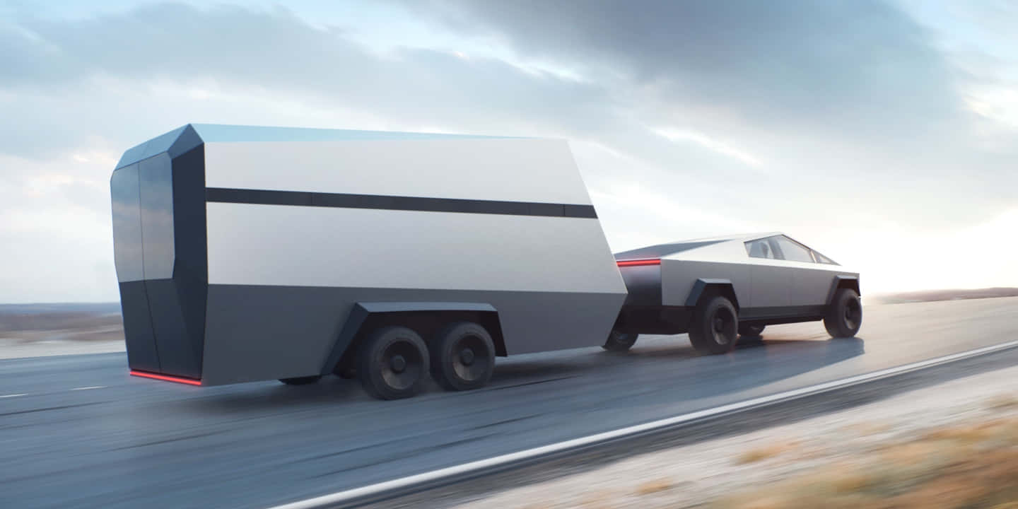 Tesla Cybertruck 桌布 壁紙 — 一輛未來感十足的銀色 Tesla Cybertruck 在陰天下拖著一個相配的棱角拖車行駛在沙漠公路上。