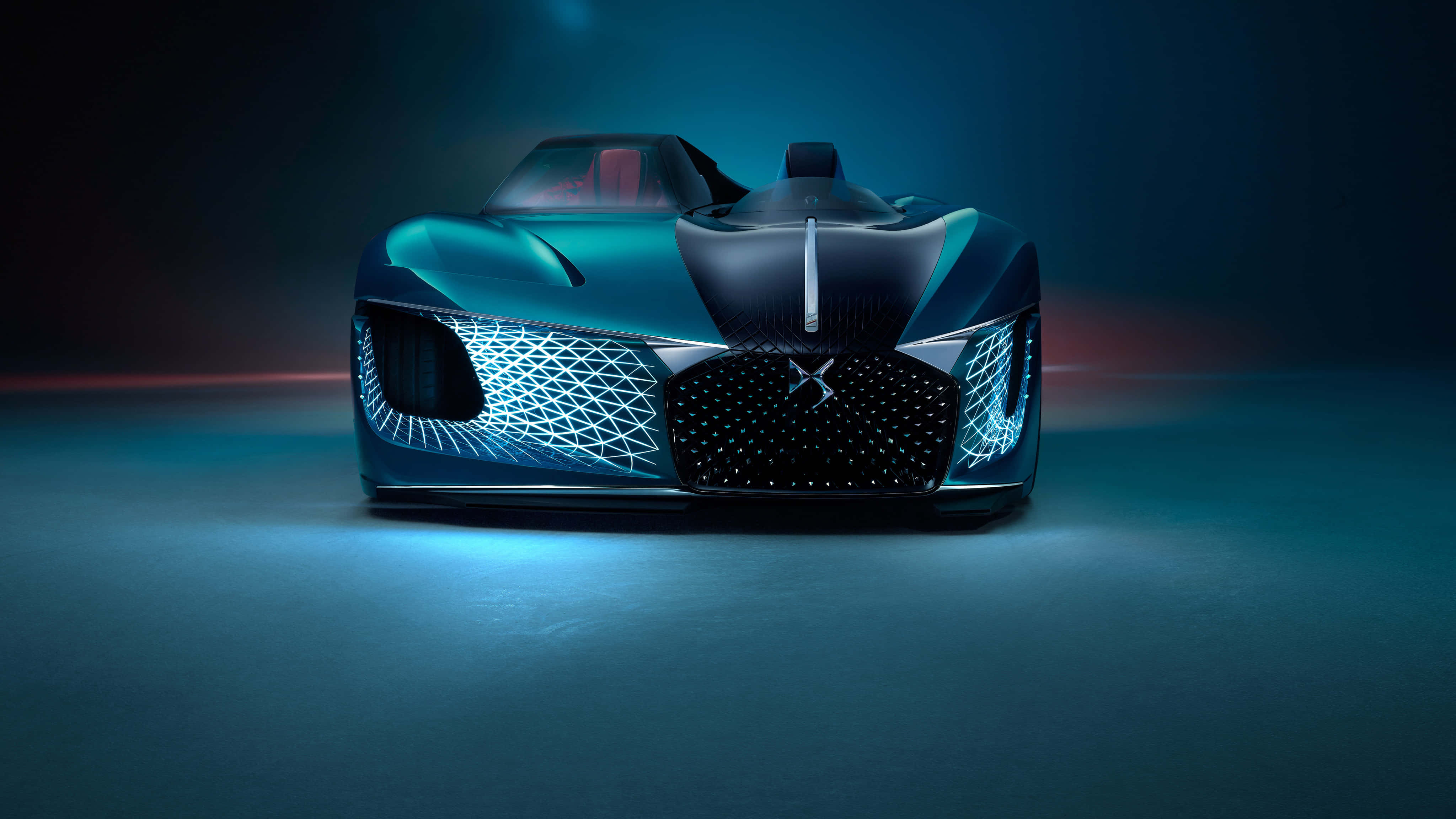 Ds Automobiles 桌布 壁紙 — 一輛未來感十足的青綠色跑車，在戲劇性的攝影棚燈光下，展現發光的藍色網格頭燈和流線型空氣動力學設計。