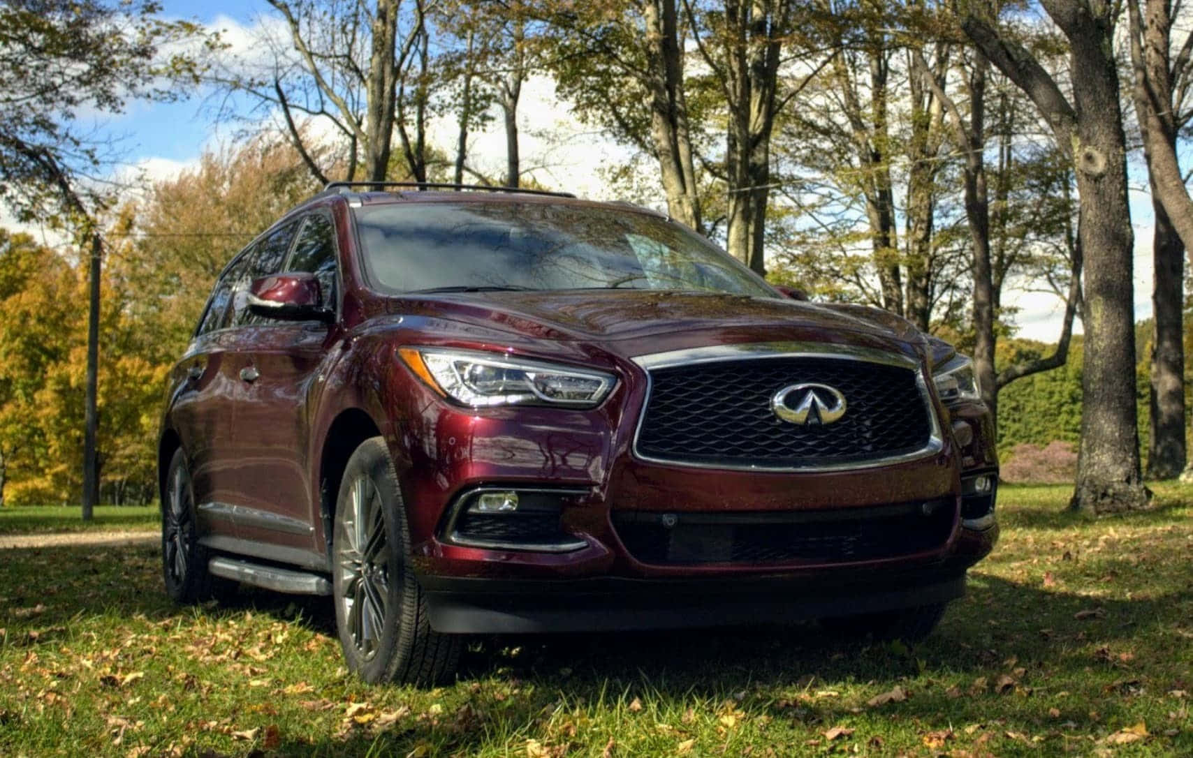 Infiniti Qx60 桌布 壁紙 — 一輛栗色 Infiniti SUV 停在草地上，周圍是秋日金葉的樹木和清澈的藍天。