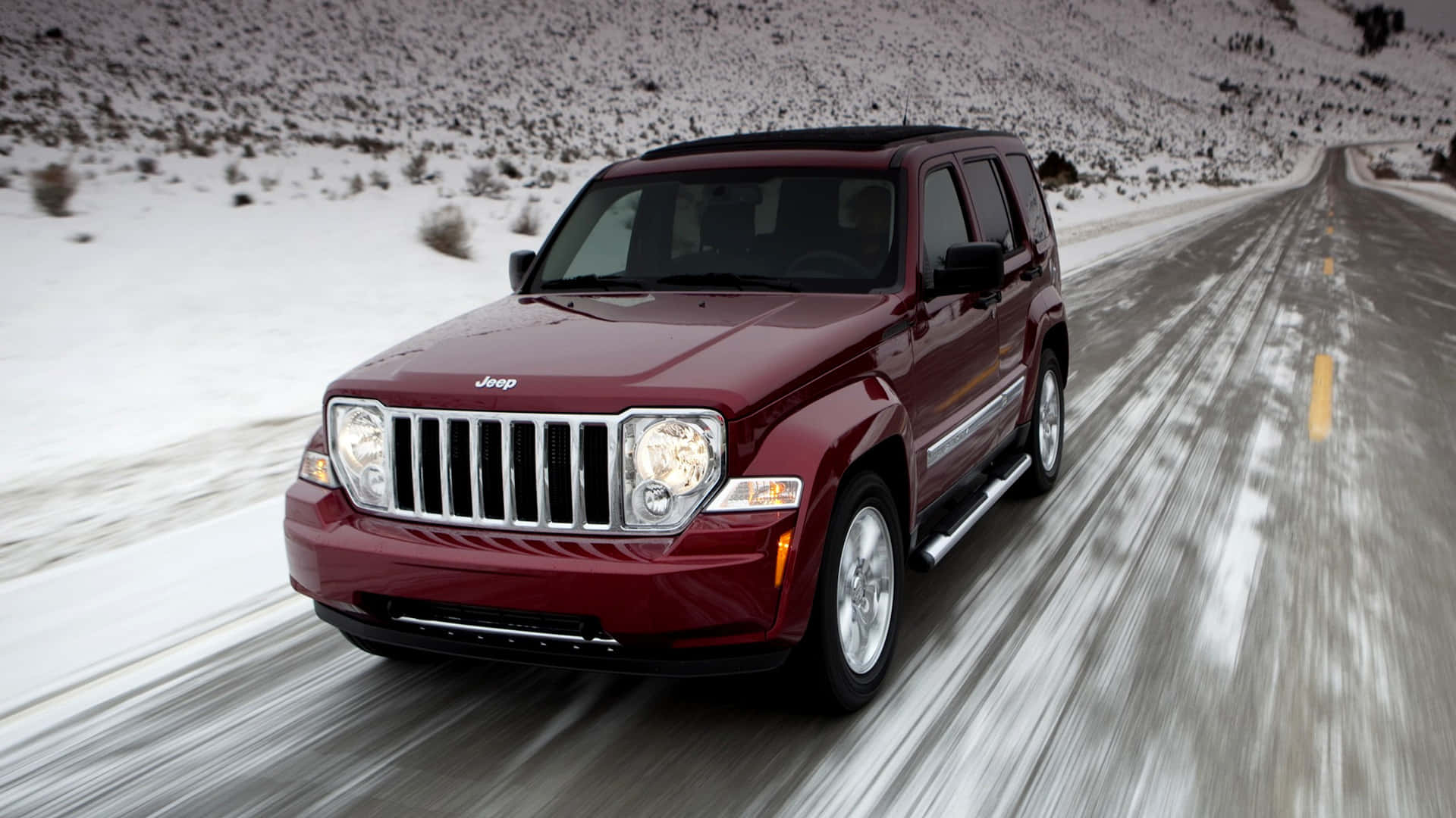 Jeep Liberty 桌布 壁紙 — 一輛栗色Jeep Liberty在雪山上飛馳，動態模糊強調其動感。