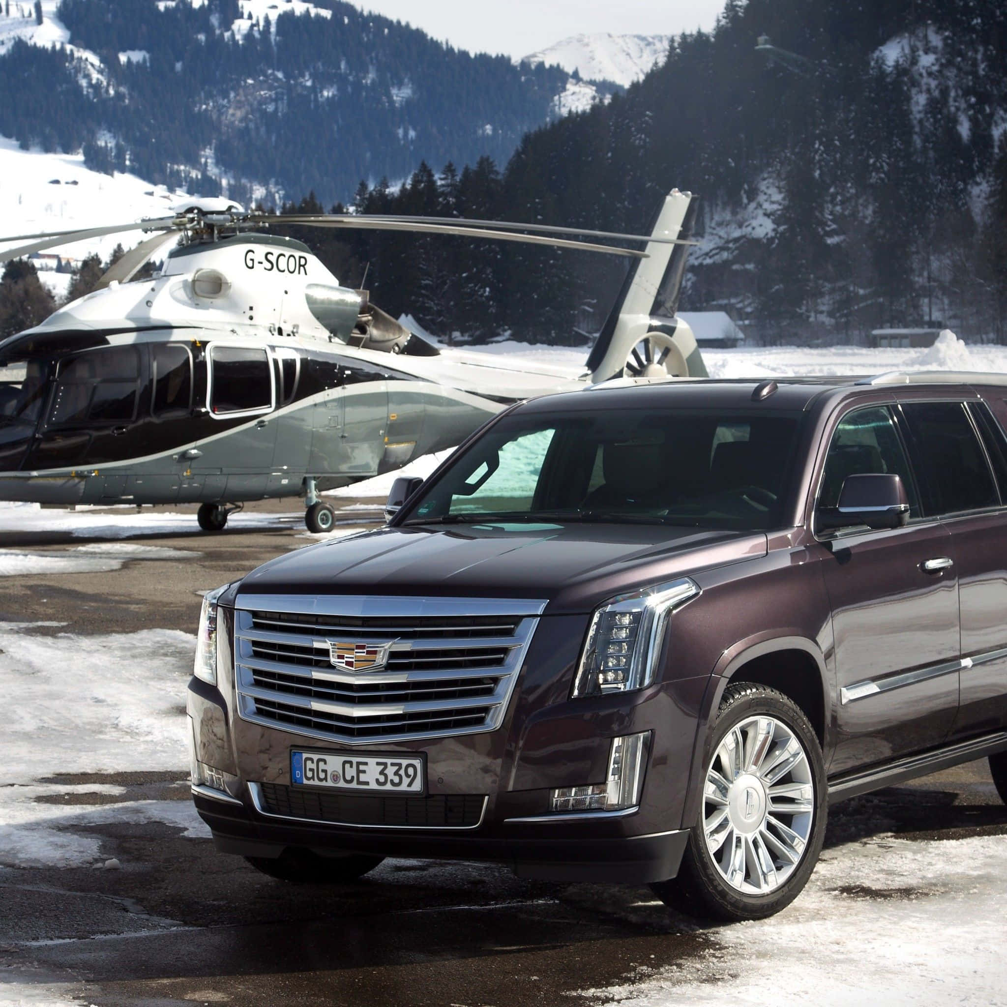 Cadillac Escalade 桌布 壁紙 — 一輛栗色的Cadillac Escalade停放在私人直升機旁，位於積雪的山頂直升機停機坪上。