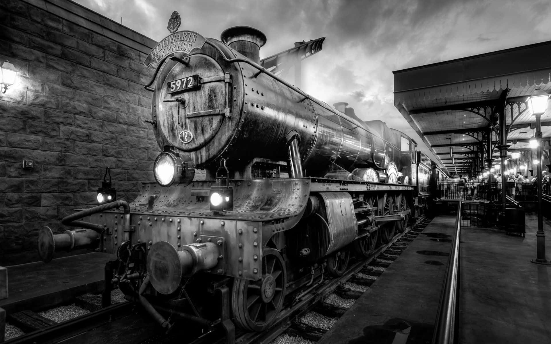 The Hogwarts Express Train 桌布 壁紙 — 一輛標有「Hogwarts Express」的雄偉蒸汽火車頭，在戲劇性的暮色天空下停靠在車站月台上。