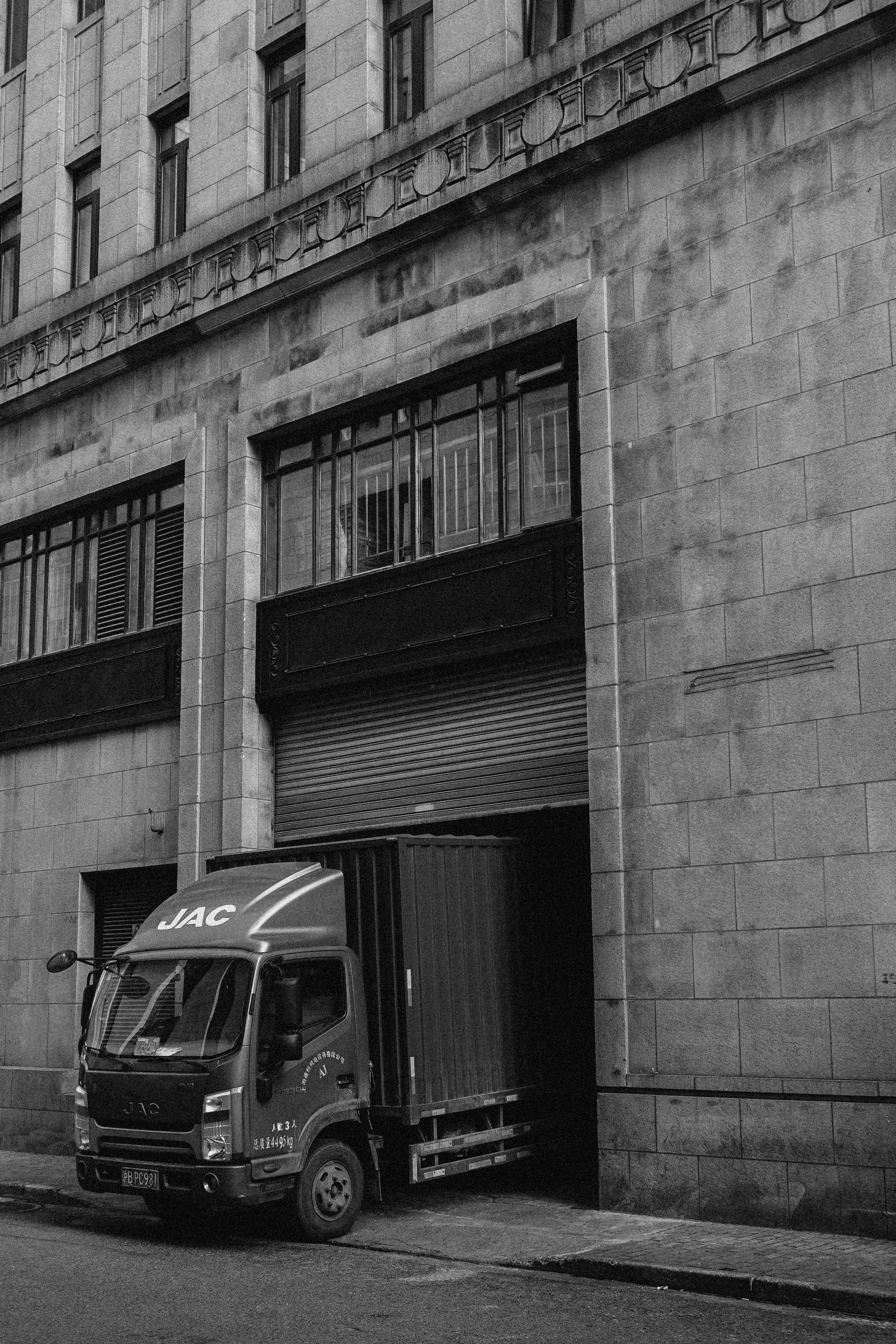 Truck 桌布 壁紙 — 一輛江淮卡車停在一個風化石建築的裝卸碼頭旁的黑白照片，建築帶有華麗的建築細節。
