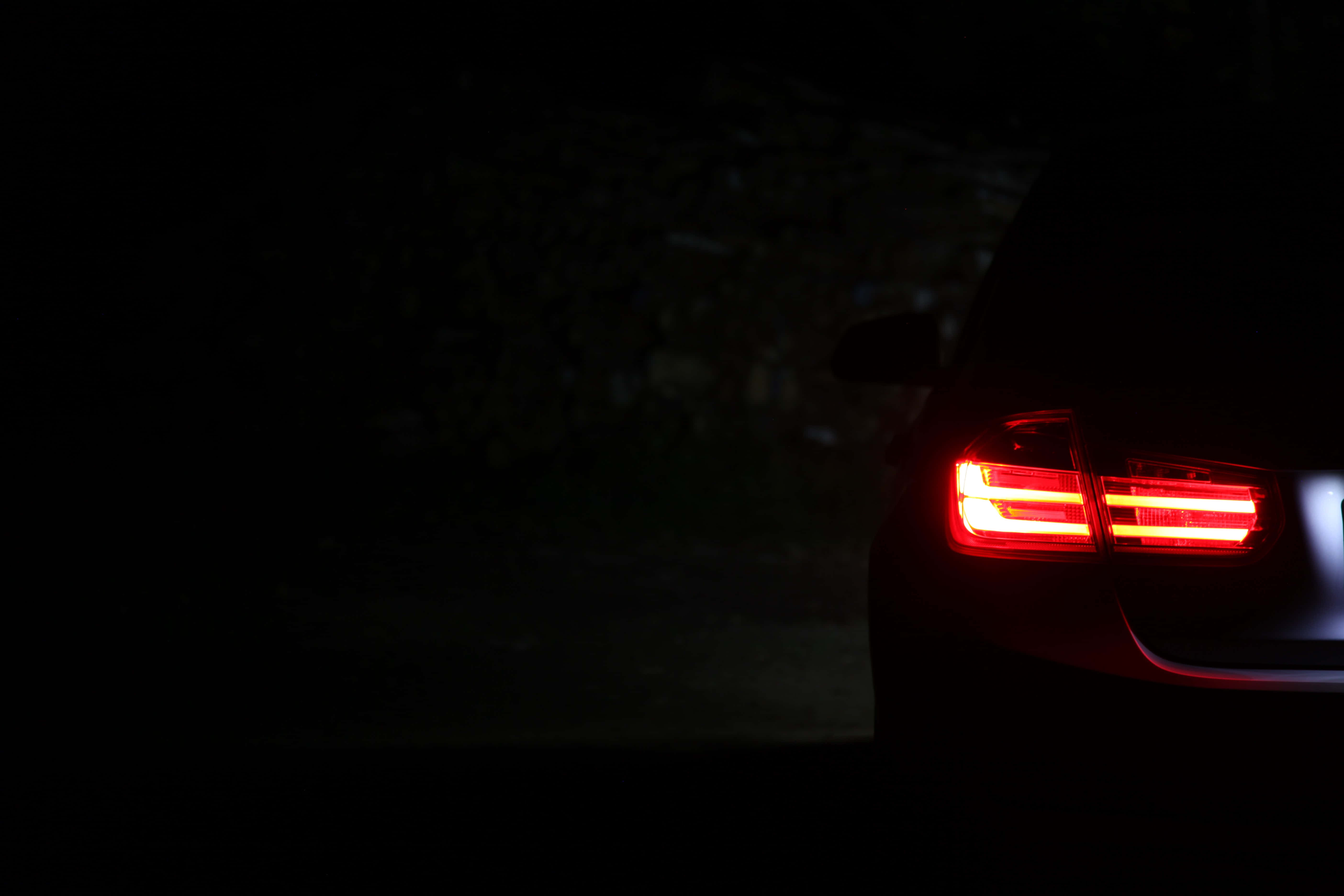 Bmw 328 桌布 壁紙 — 一輛汽車發光的紅色尾燈刺穿了夜間路邊場景的黑暗。