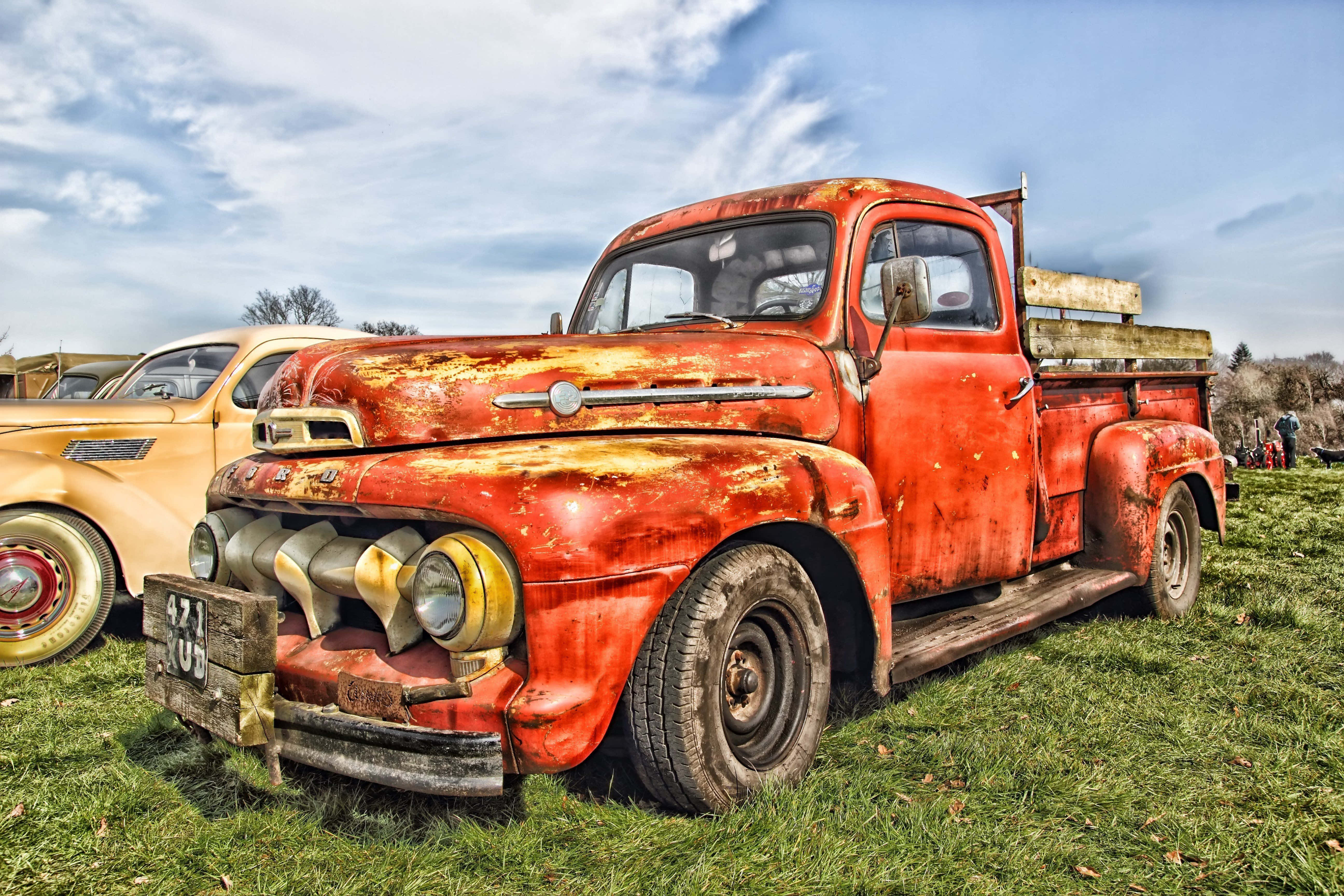Ford Truck 桌布 壁紙 — 一輛油漆剝落、飽經風霜的紅色復古小貨車停放在草地上，天空局部多雲。