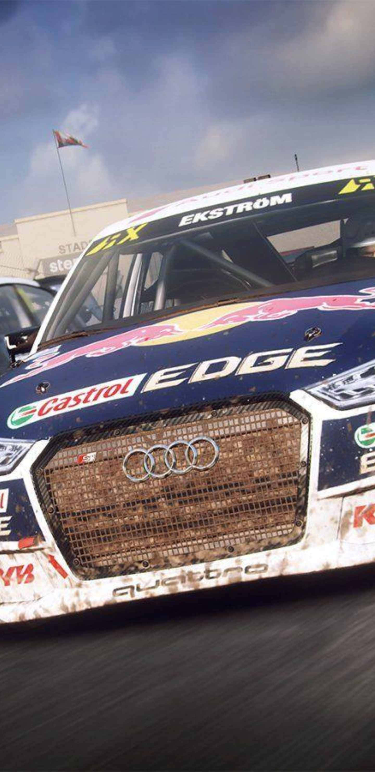 Android Dirt Rally 桌布 壁紙 — 一輛沾滿泥濘的奧迪賽車，帶有紅牛和嘉實多品牌標誌，在多雲的天空下疾馳而過。