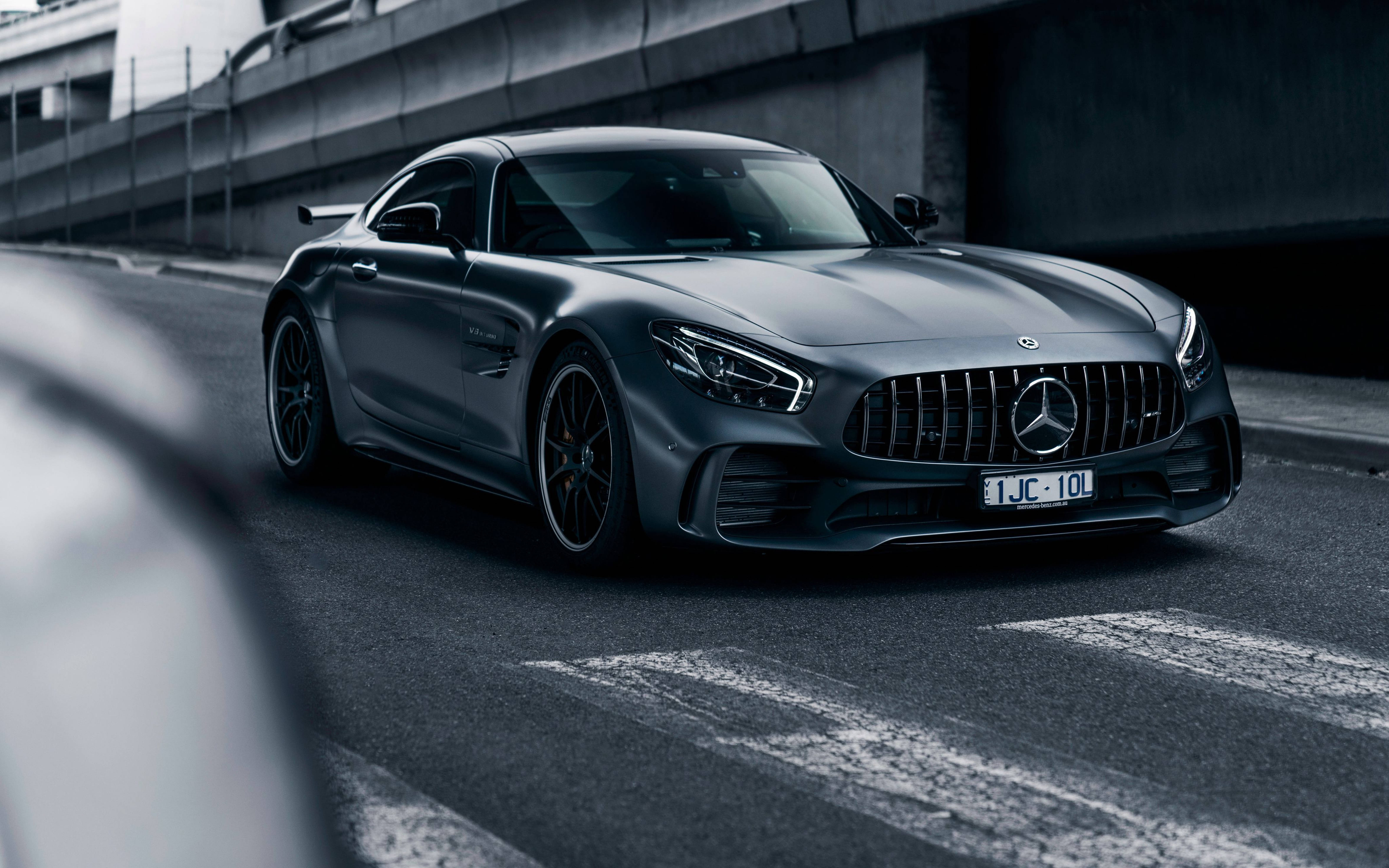 黑色 桌布 壁紙 — 一輛流線型啞光灰色梅賽德斯-AMG GT R跑車停在天橋下的混凝土城市道路上。