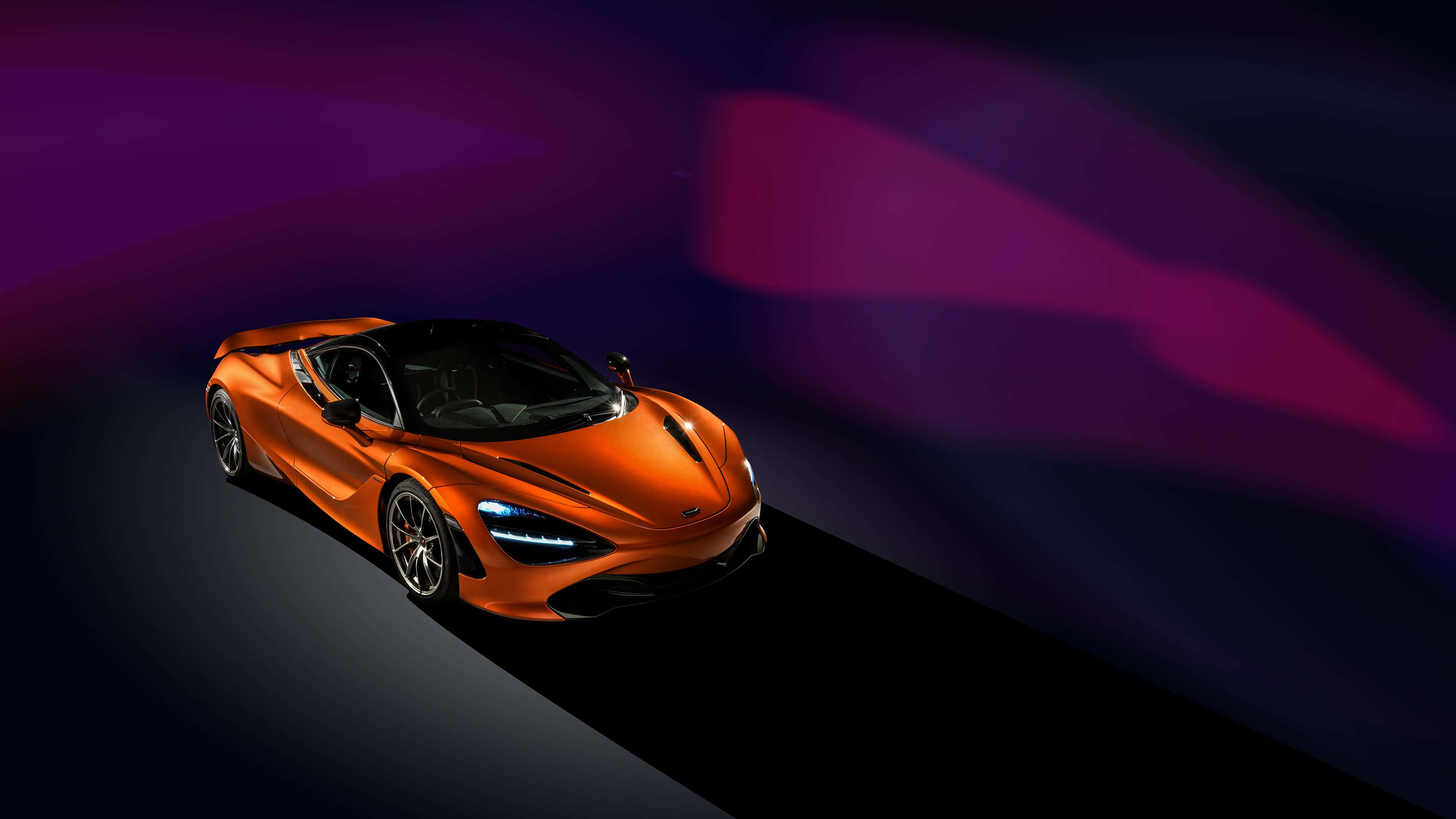 4K Mclaren 720s 桌布 壁紙 — 一輛流線型橙色跑車在黑暗隧道中疾馳，伴隨充滿活力的紫色和洋紅色光條。