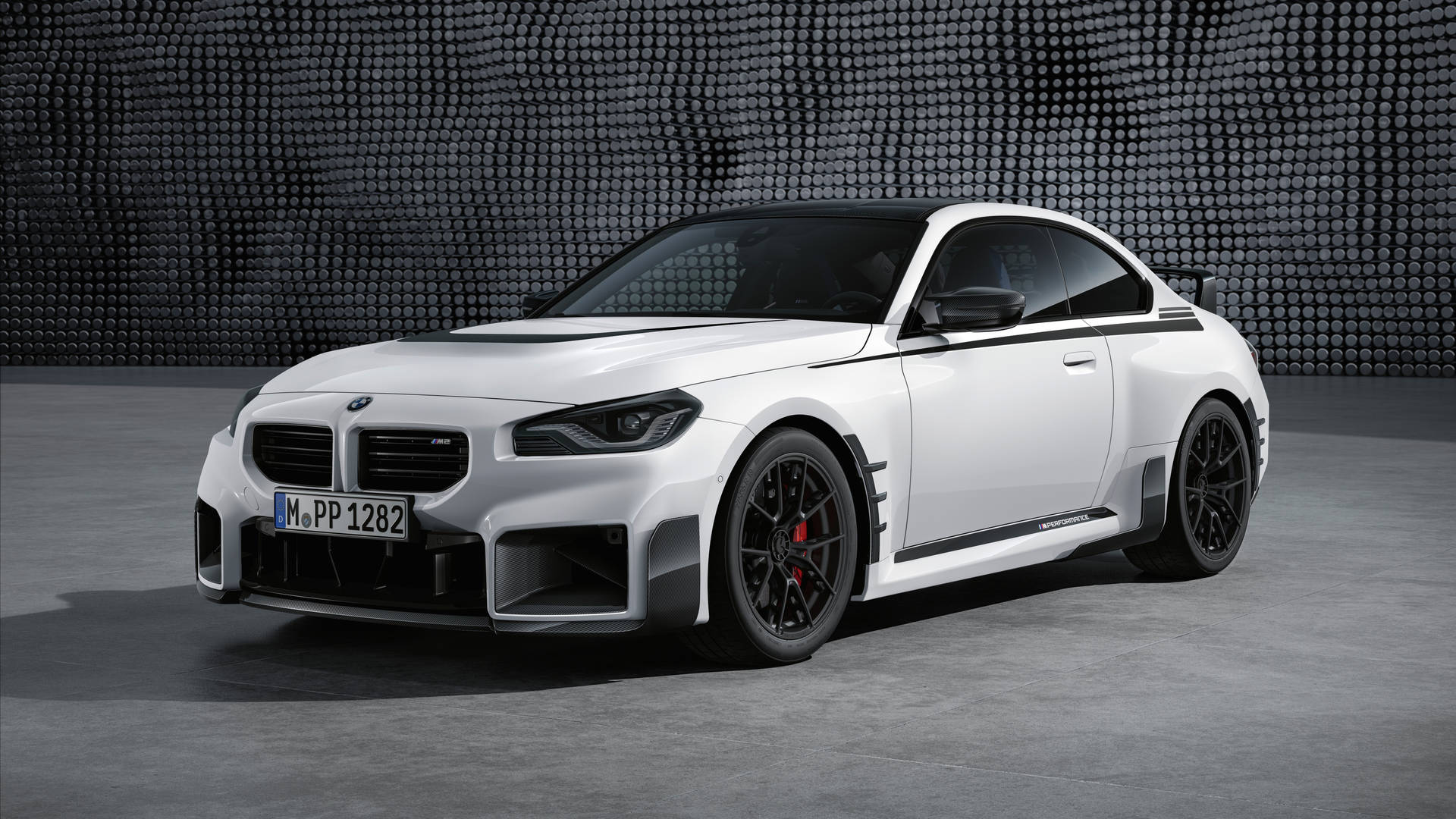 白色BMW M2 Competition跑車，黑色飾邊和紅色制動器，在攝影棚環境中。