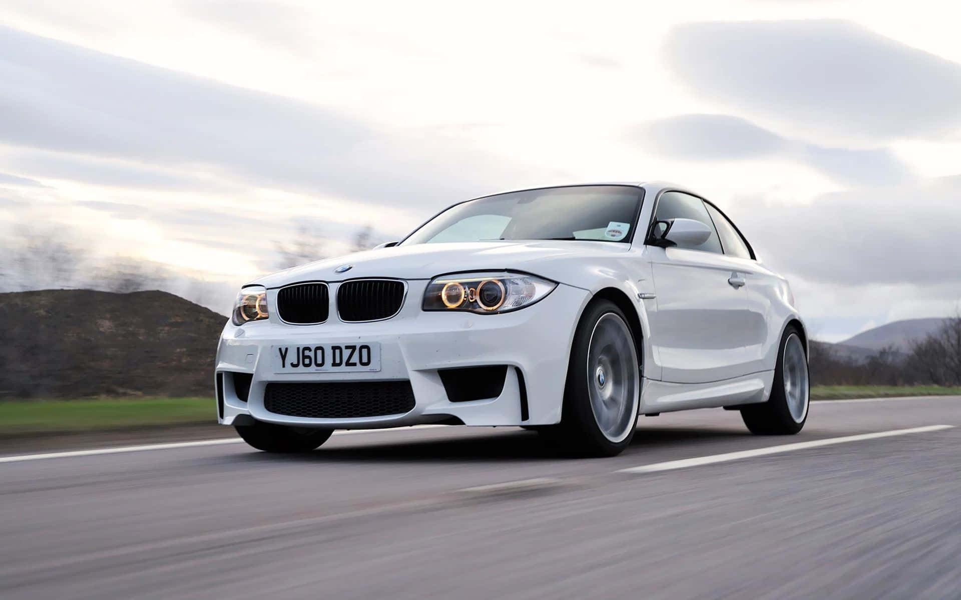 Bmw 1 Series 桌布 壁紙 — 一輛流線型白色BMW跑車在陰天的鄉村道路上高速行駛，呈現動態模糊效果。