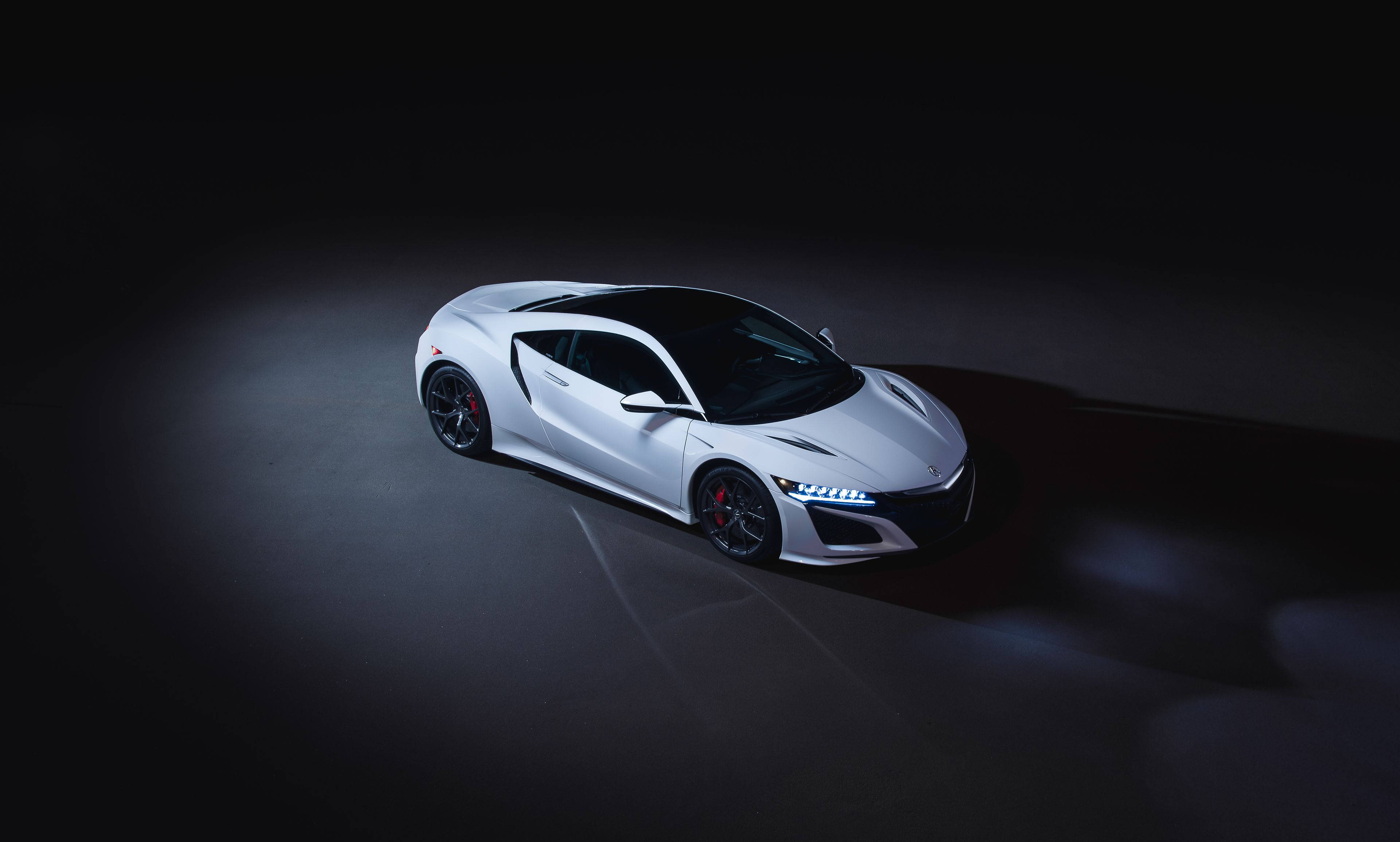 Acura 桌布 壁紙 — 一輛流線型白色跑車在黑暗的攝影棚地板上被聚光燈照亮，投射出戲劇性的陰影。