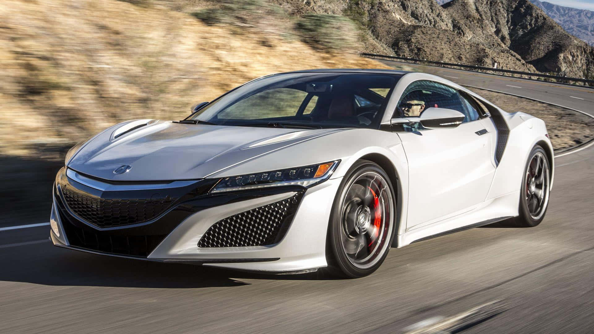 Acura Nsx 桌布 壁紙 — 一輛流線型白色跑車沿著蜿蜒的山路飛馳，背景是模糊的岩石地形。