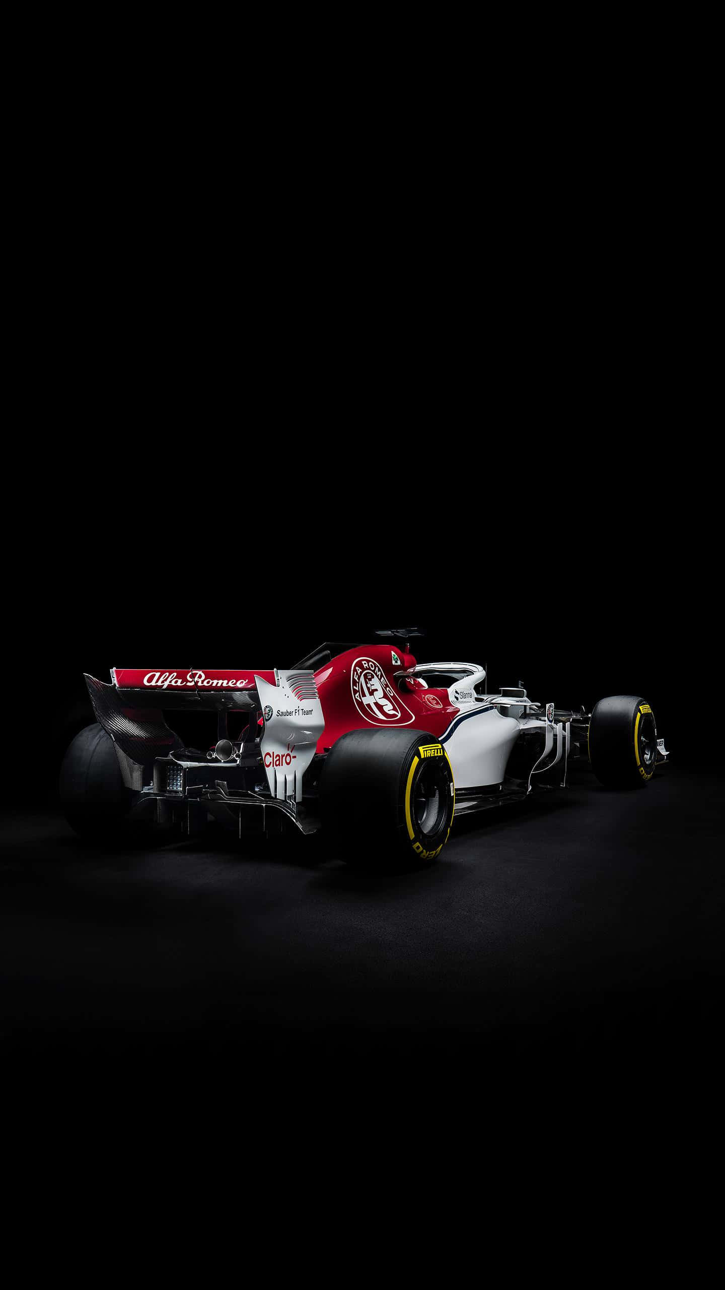Formula 1 iPhone 桌布 壁紙 — 一輛流線型的愛快羅密歐一級方程式賽車在漆黑背景下的攝影棚燈光中閃耀。