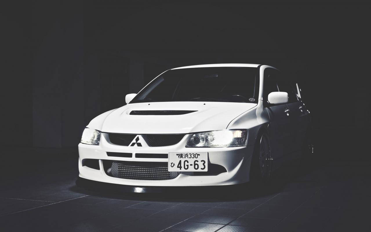 Mitsubishi 桌布 壁紙 — 一輛流線型的白色三菱Lancer Evolution在黑暗的攝影棚背景下被聚光燈照亮。